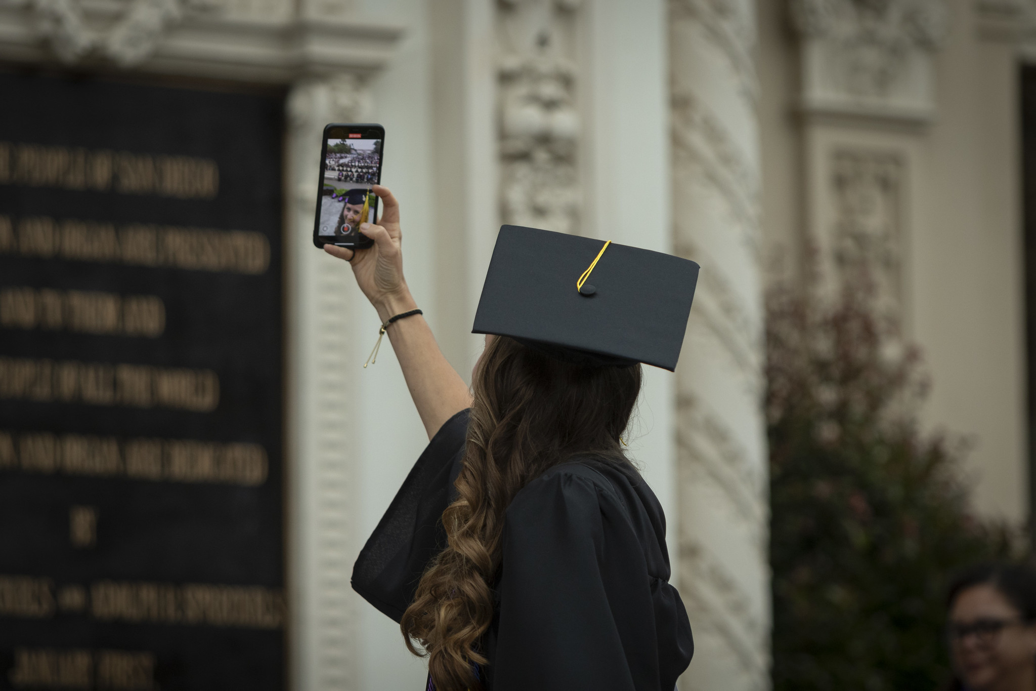 
A student on stage takes a selfing with the audience behind her.
