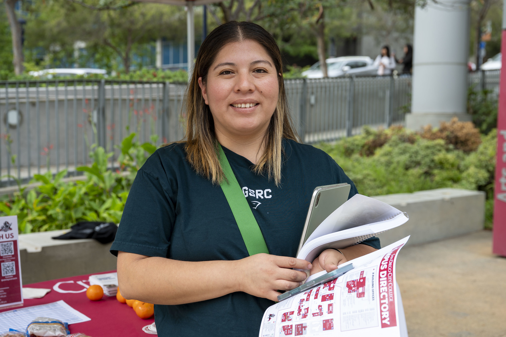 
A worker at a welcome tent is handing out campus maps.
