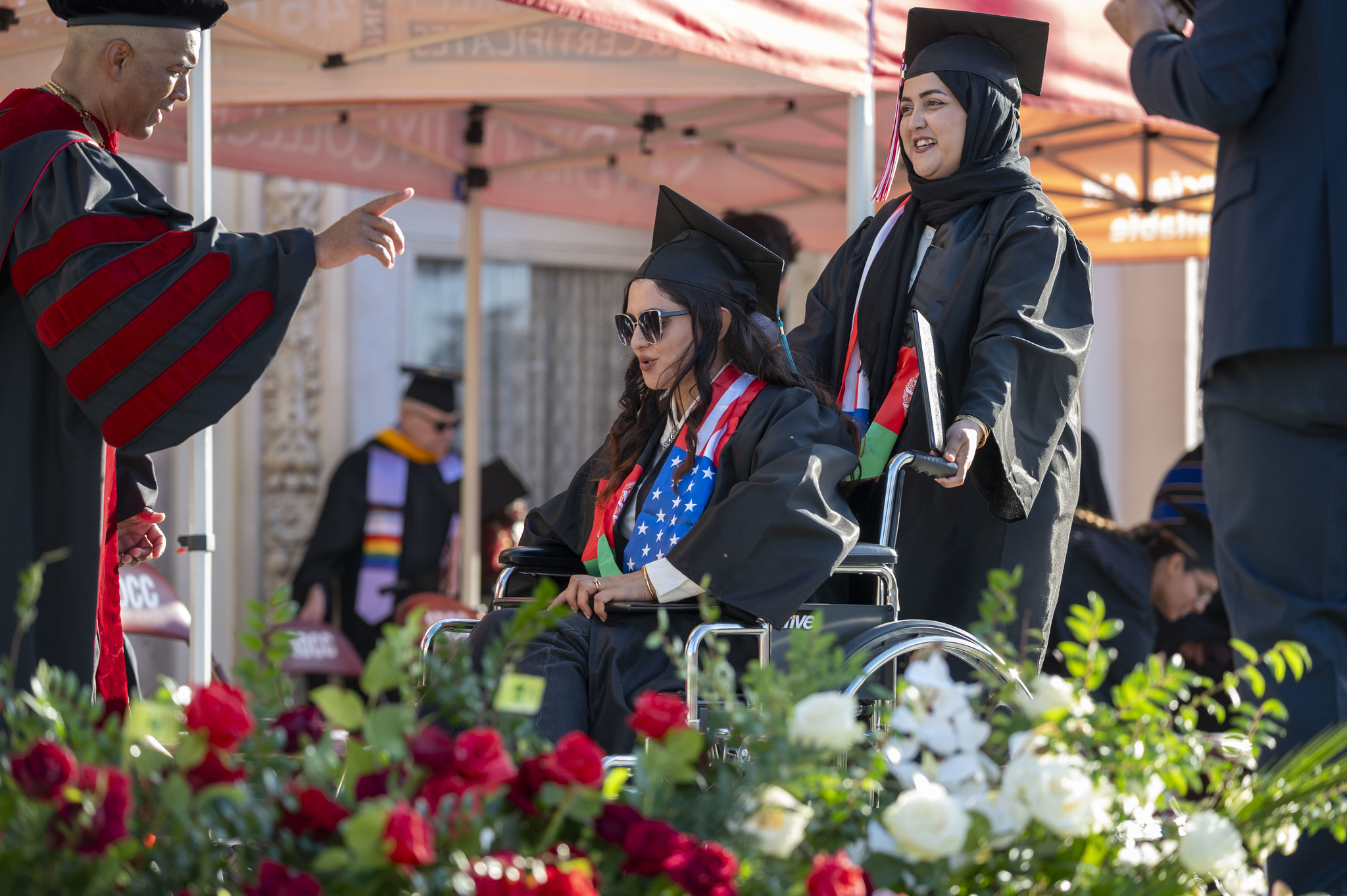 
Two graduates walk across the stage with their degrees.
