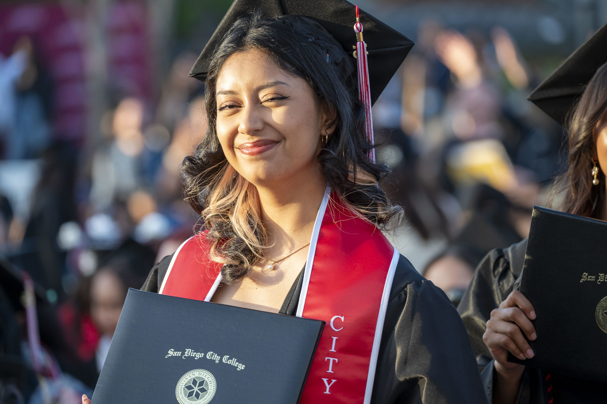 
A graduate smiles as she holds her degree
