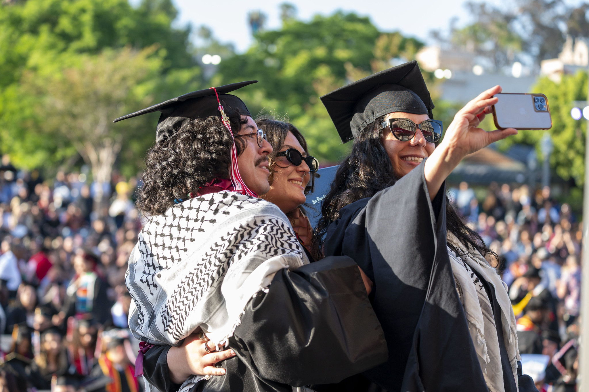 
Three grads take a selfie on stage.
