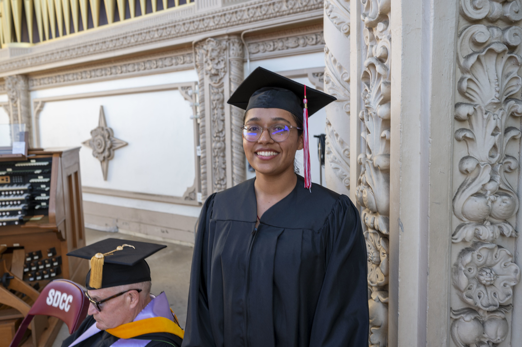 
A graduate on stage in a black cap and gown.

