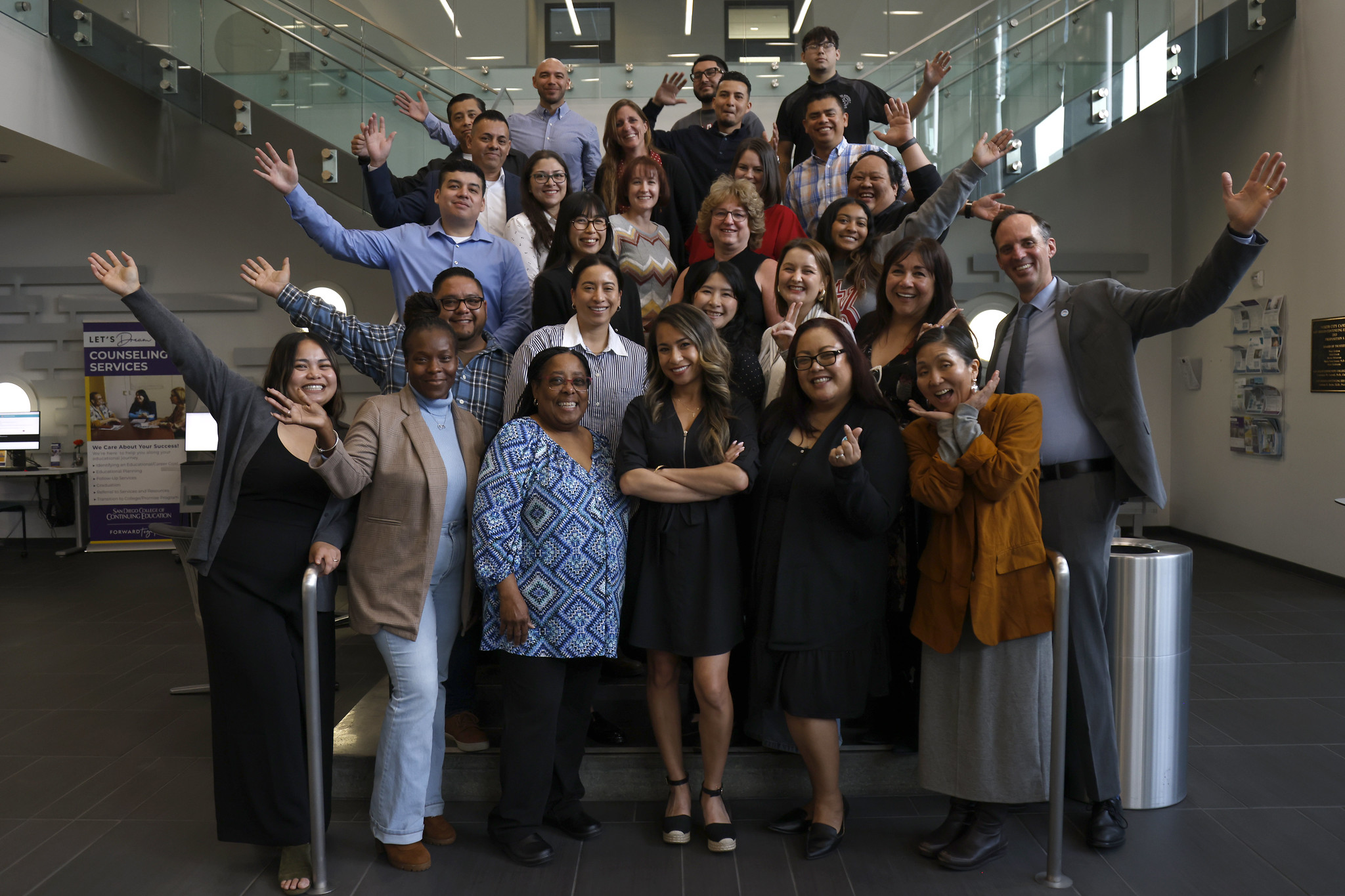 
Chancellor Gregory Smith and 27 employees in the Classified Leadership Development Academy wave while gathered on a staircase.
