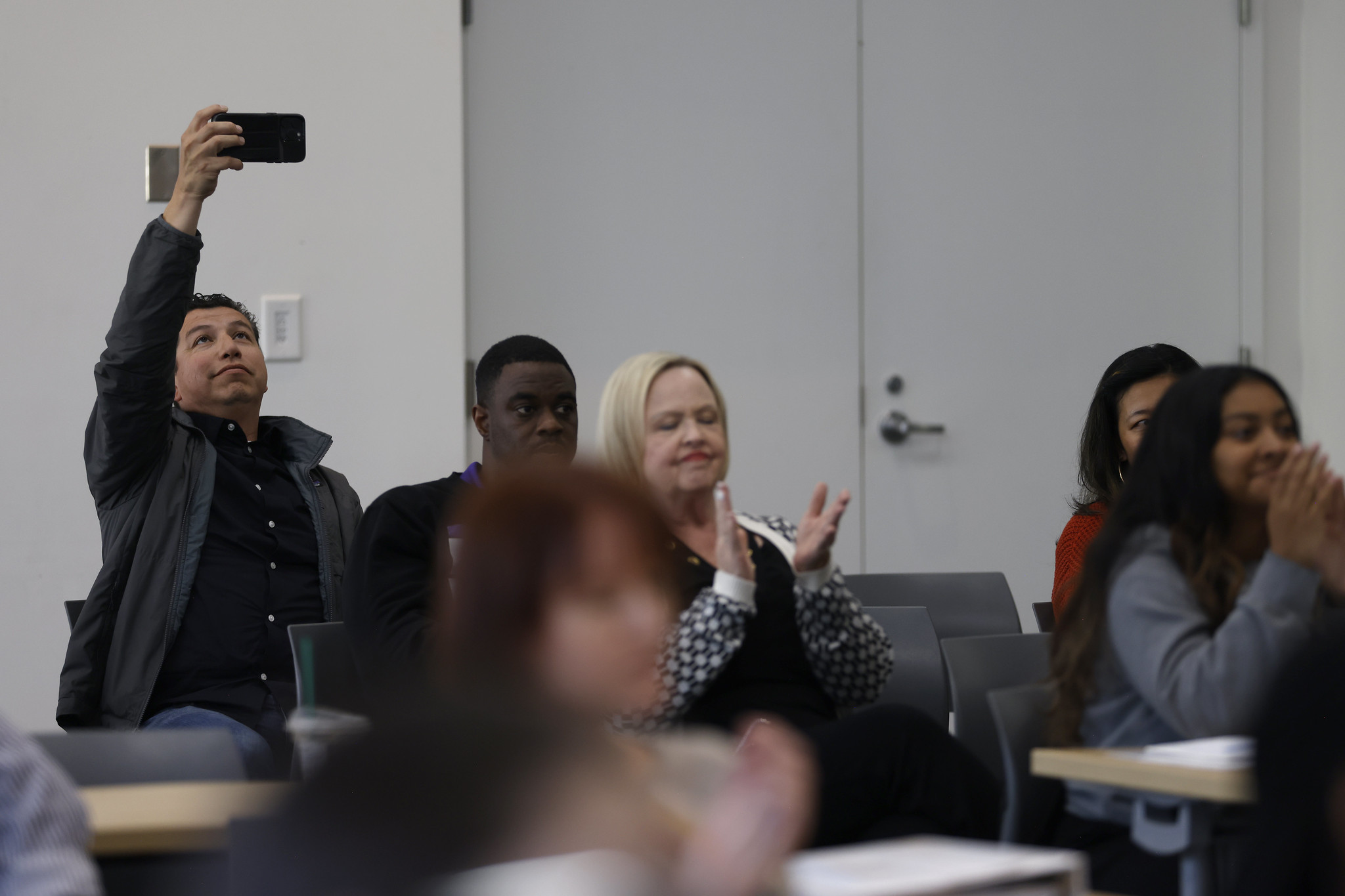 
A man in the audience holds up his cell phone to take a picture.

