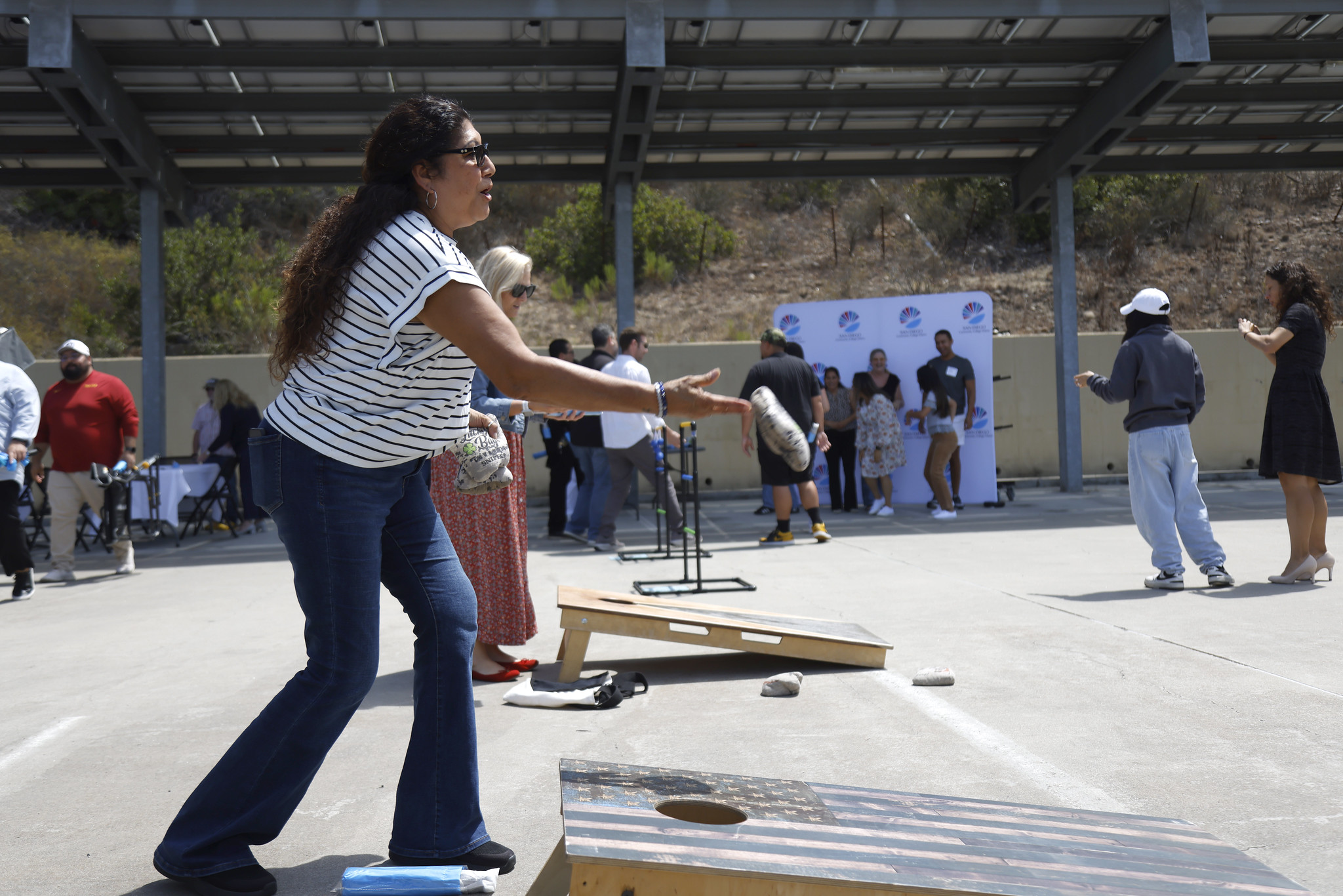 
An employee playing cornhole tosses a beanbag.
