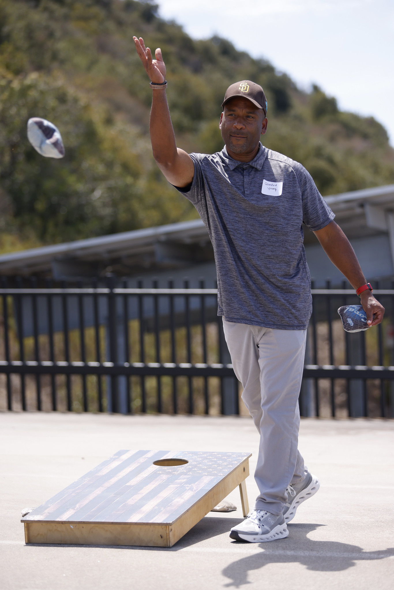 
An employee playing cornhole tosses a beanbag.
