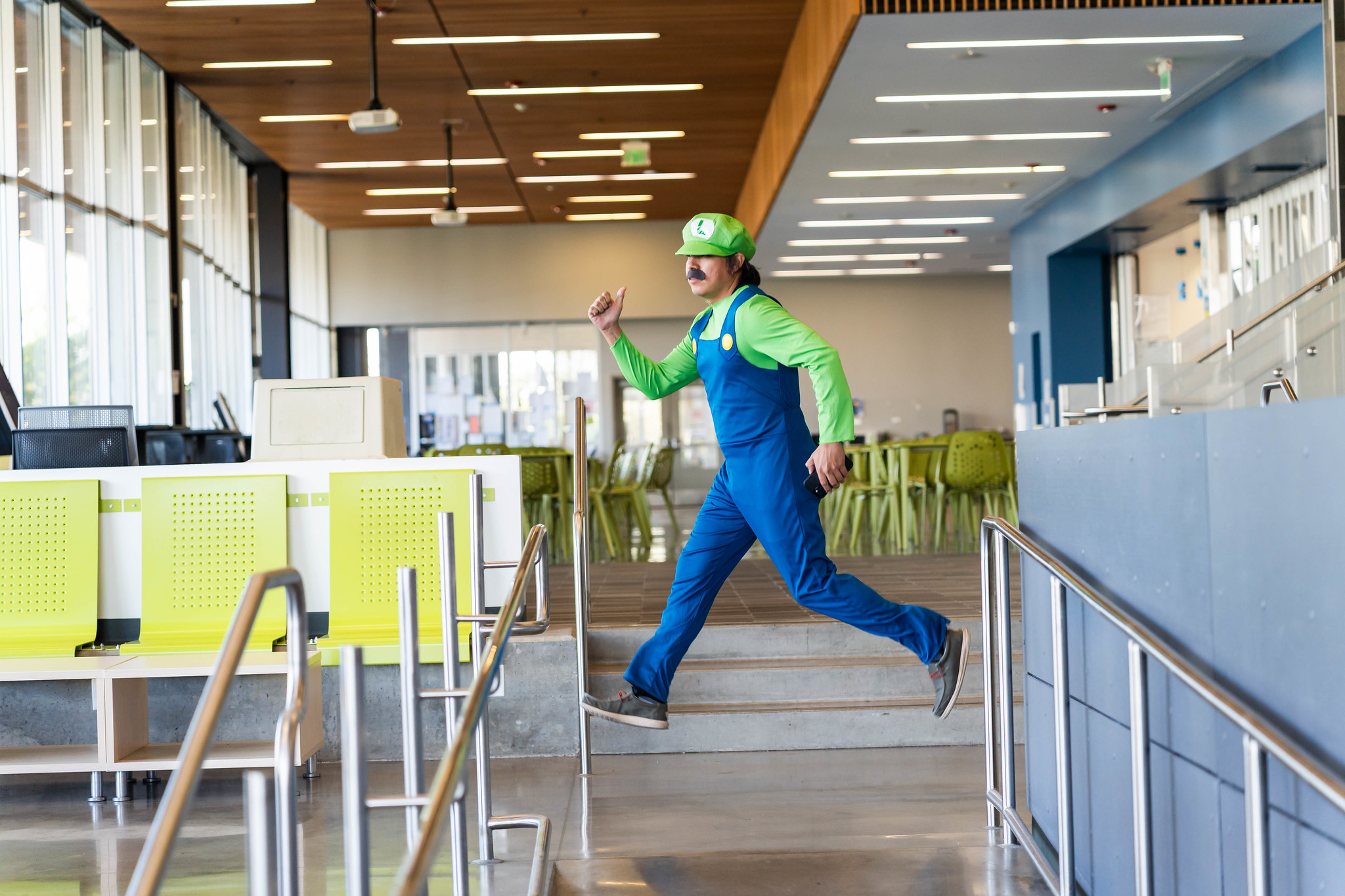 
A man in a blue and green jumpsuit dressed as Luigi.
