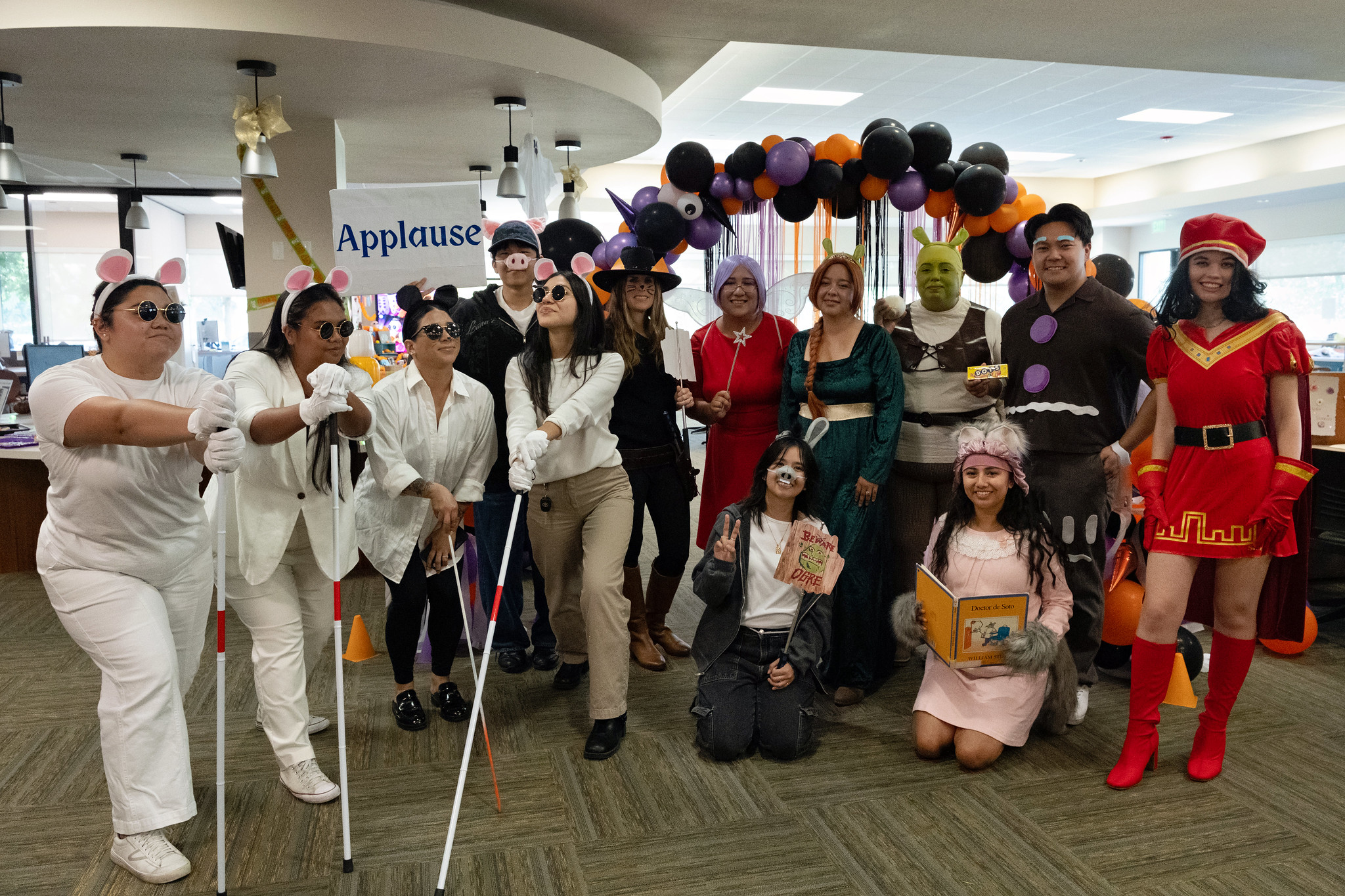 
14 people in a group costume dressed as various characters from the movie Shrek.
