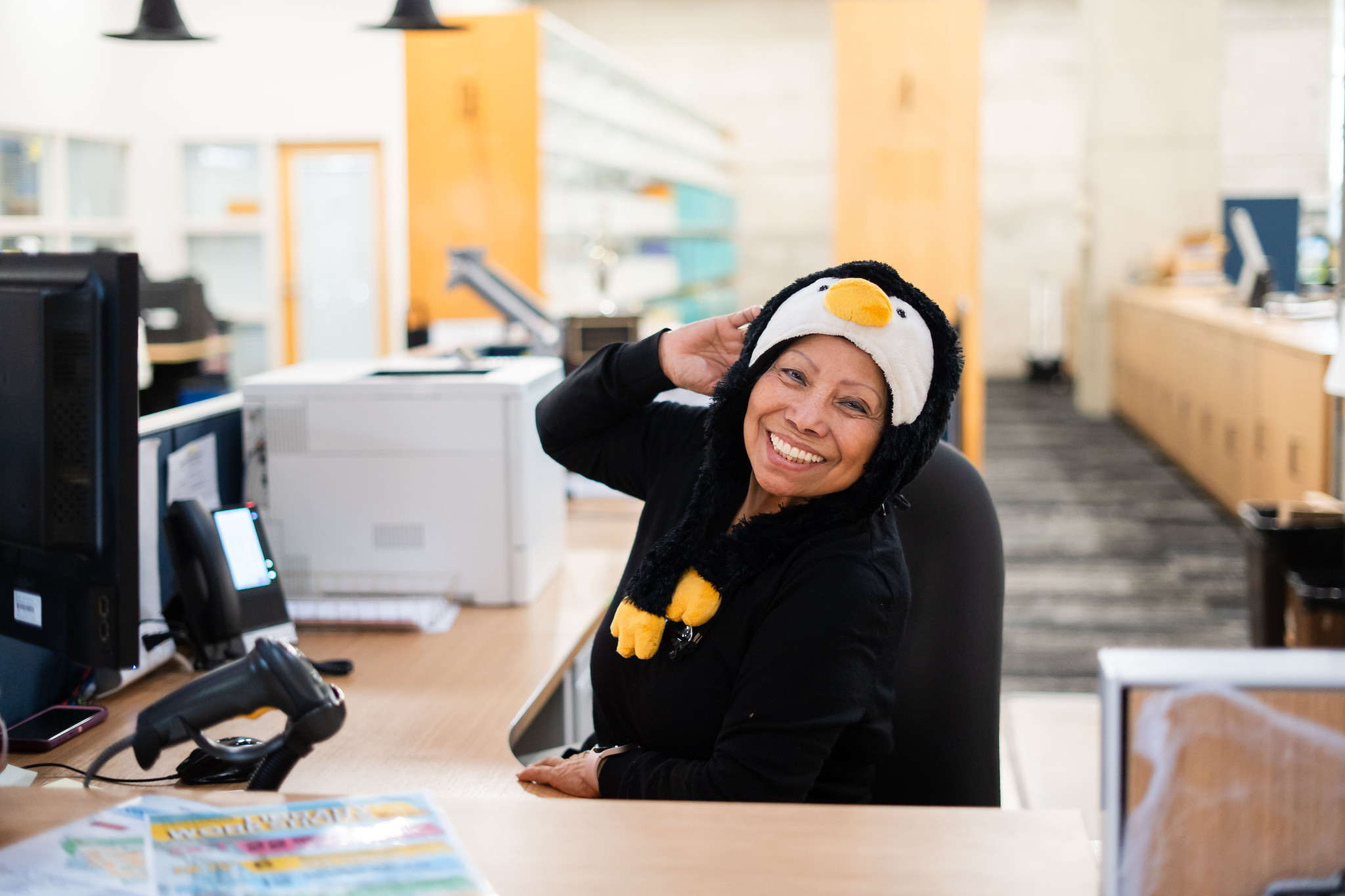 
A woman dressed as a penguin sits at her desk
