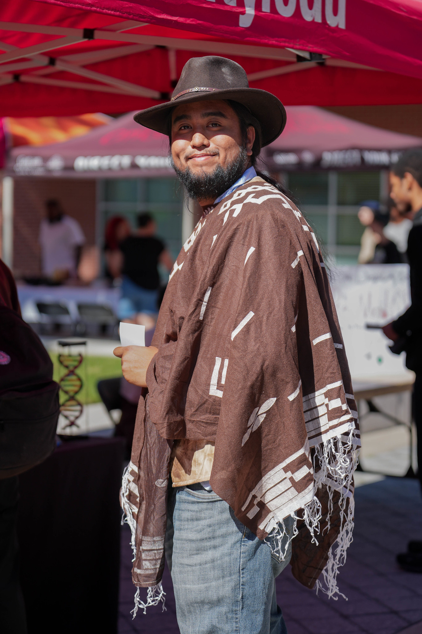 
A man in a brown pancho wearing a fedora.
