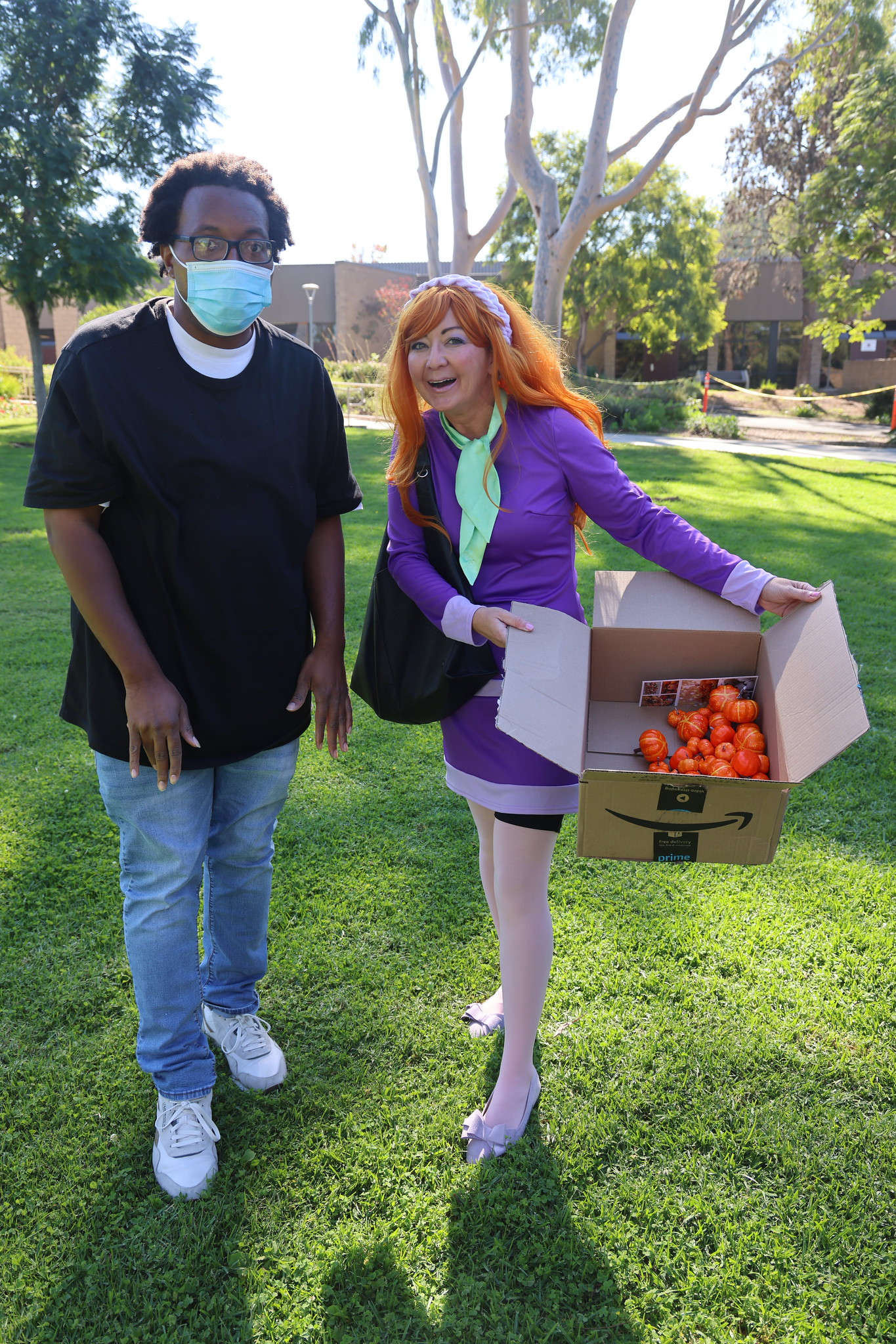
A woman dressed at Daphne from Scooby Doo with a man wearing a face mask.
