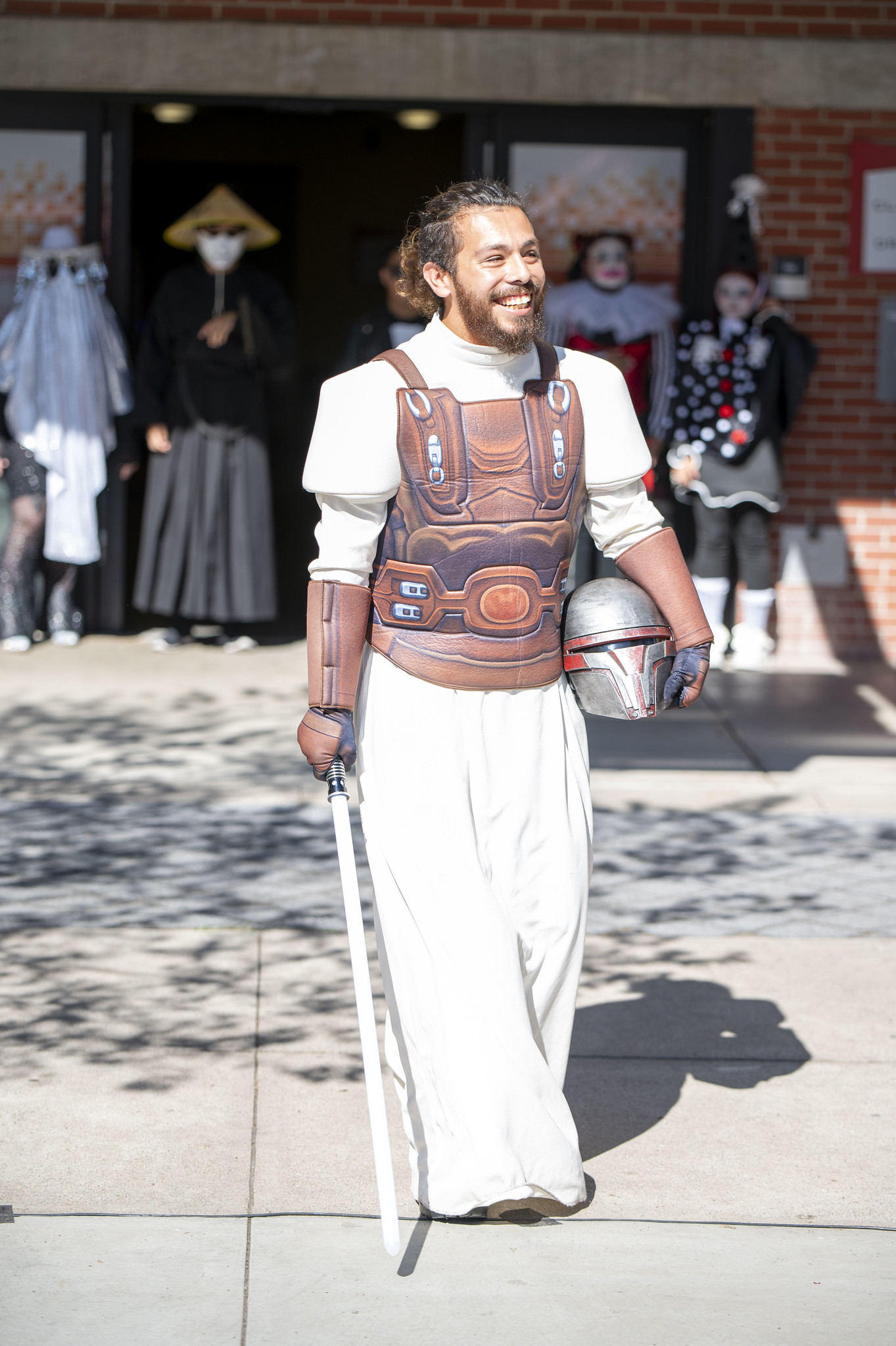 
A man wearing a Madelorian costume and carrying a white light saber.
