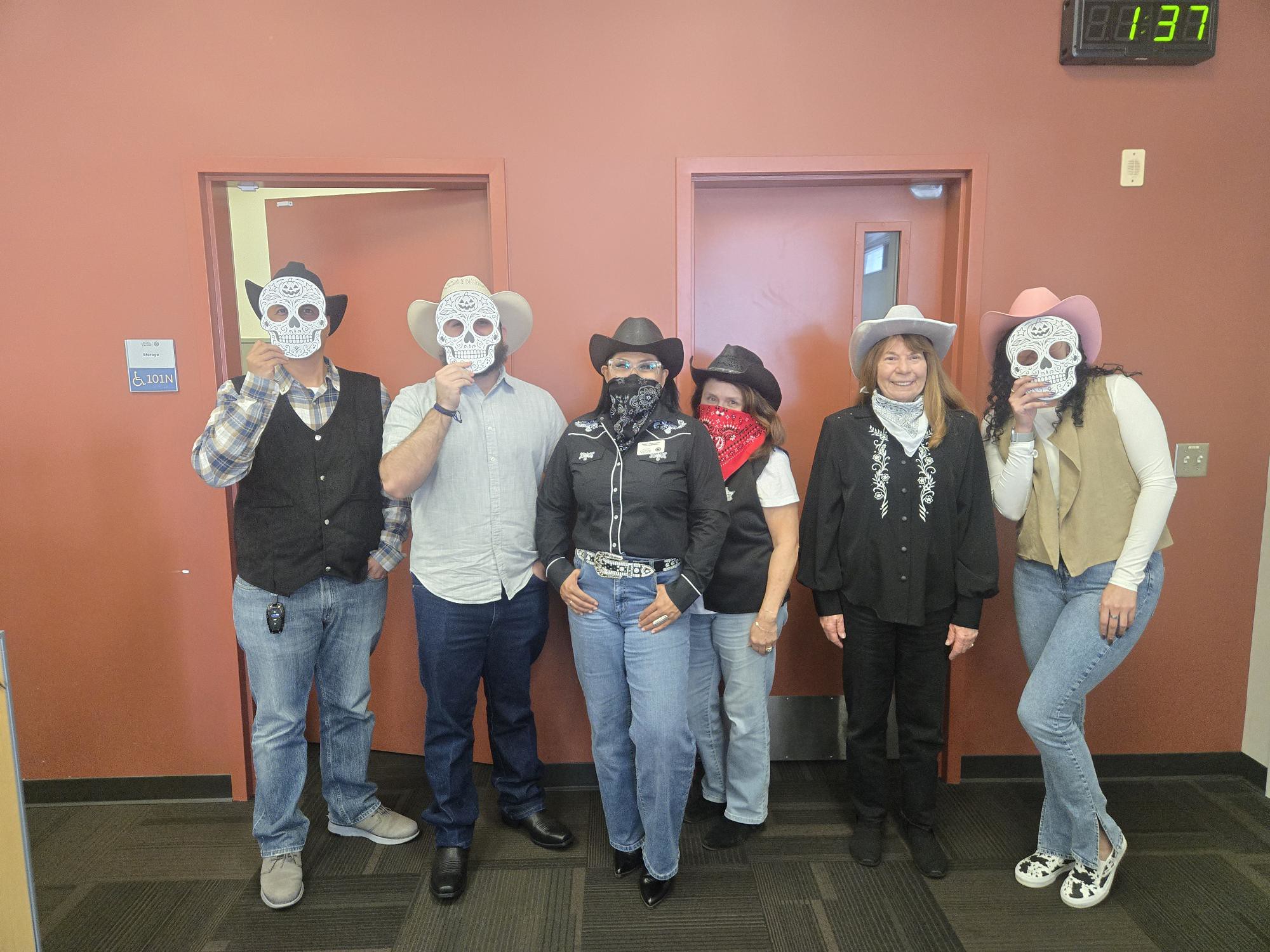 
Six people dressed as cowboys. Three are covering their faces with a skeleton mask.
