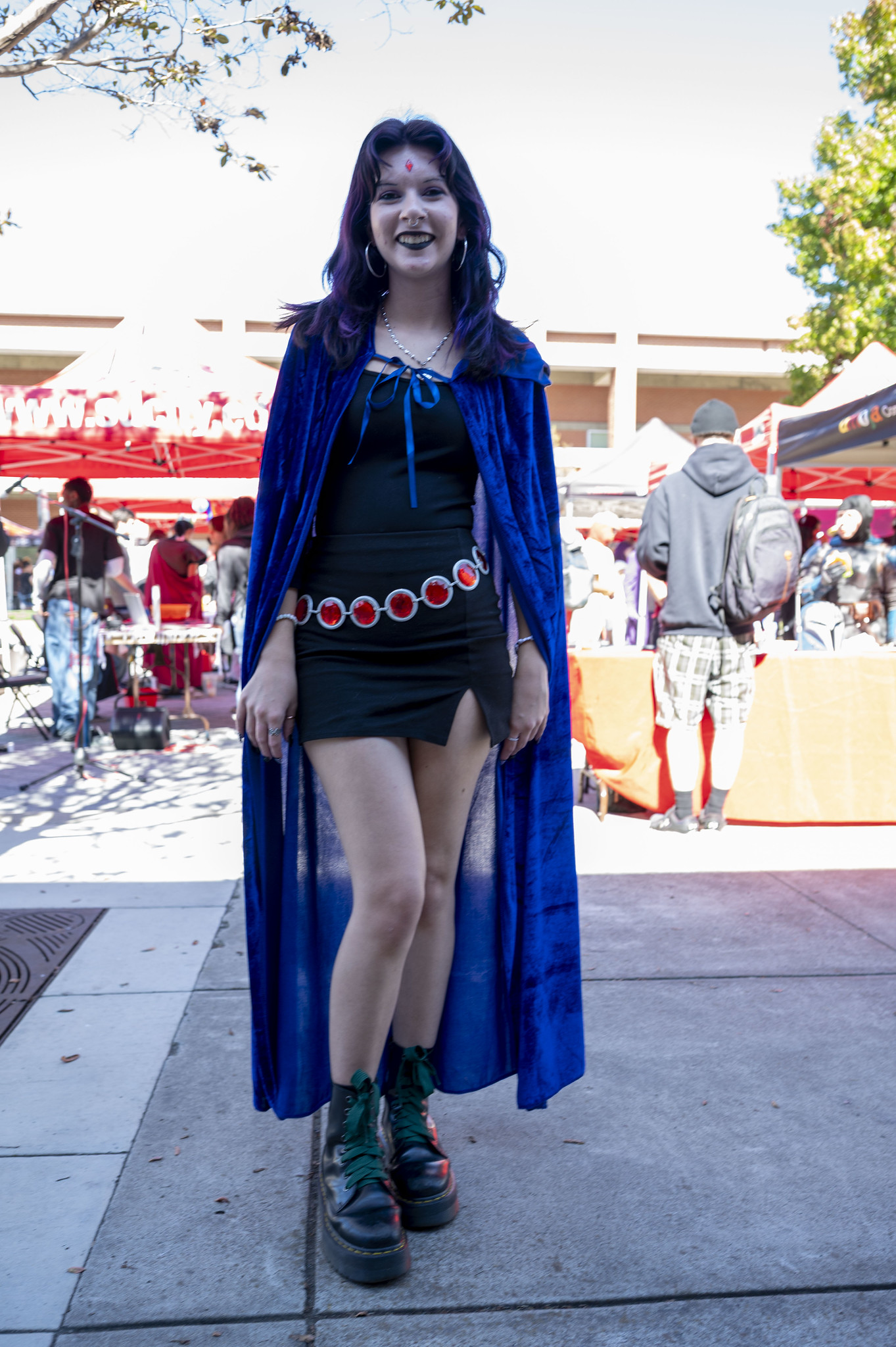 
A lady in a black dress and a blue velvet cape.
