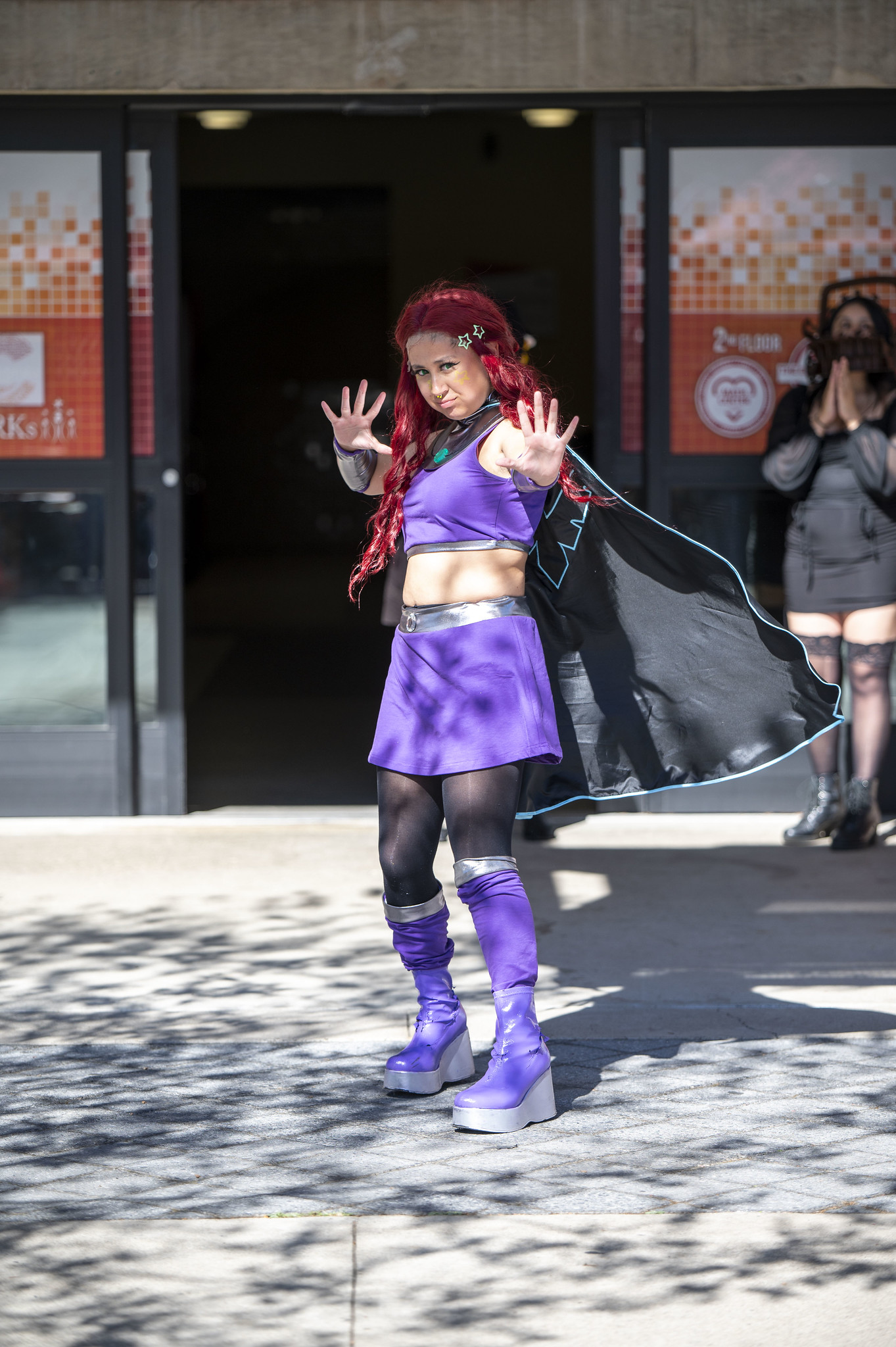 
A woman dressed as a wizard in a purple skirt, top and cape.

