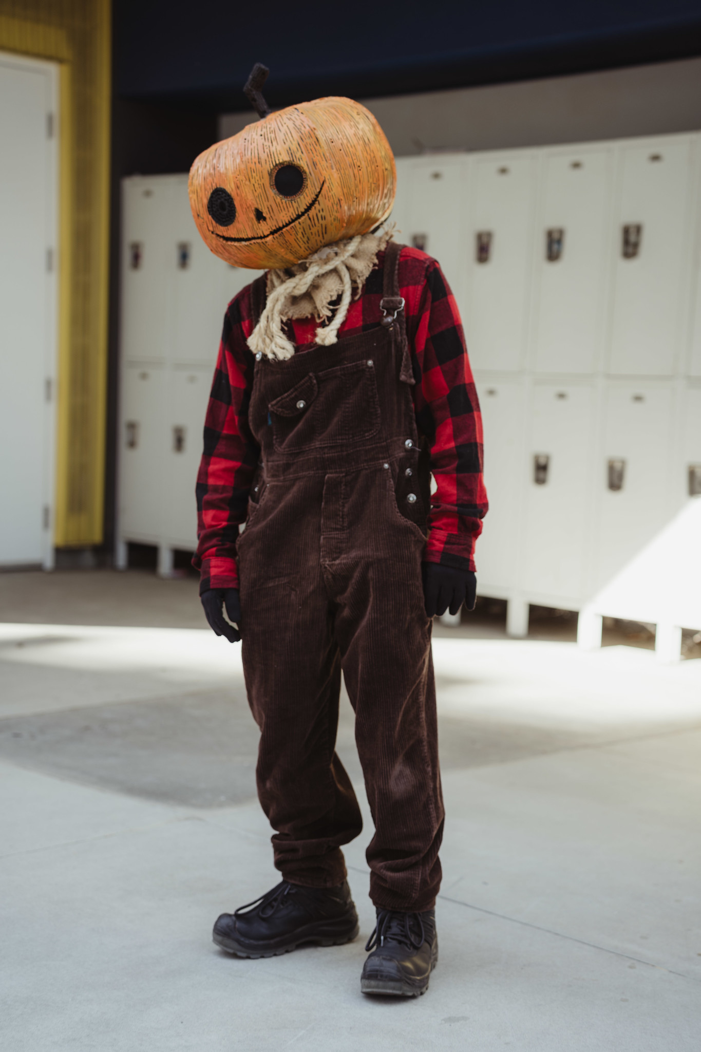 
Someone in brown overalls, a red flannel shirt wearing a giant pumpkin head.
