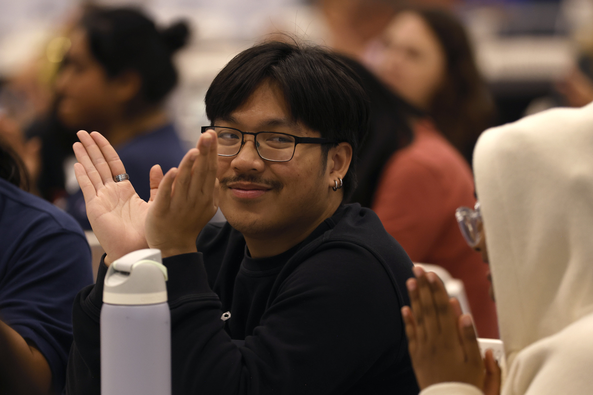 
A student in the audience applauds.
