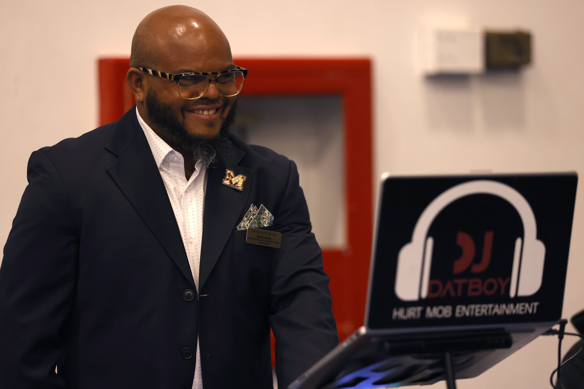 
A man in a suit in front of a DJs laptop.
