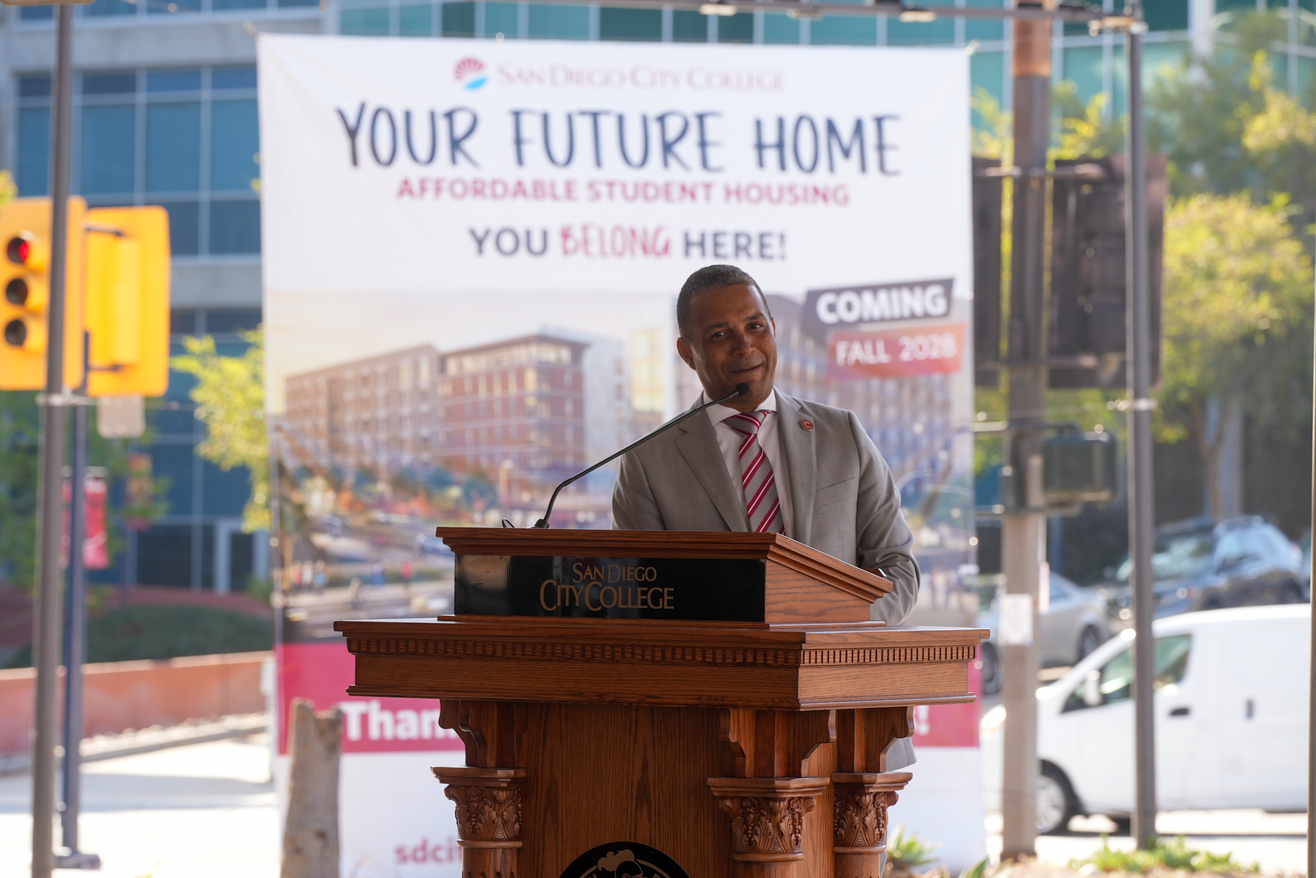 
City College President Ricky Shabazz at a podium speaking to the audience a the housing event.
