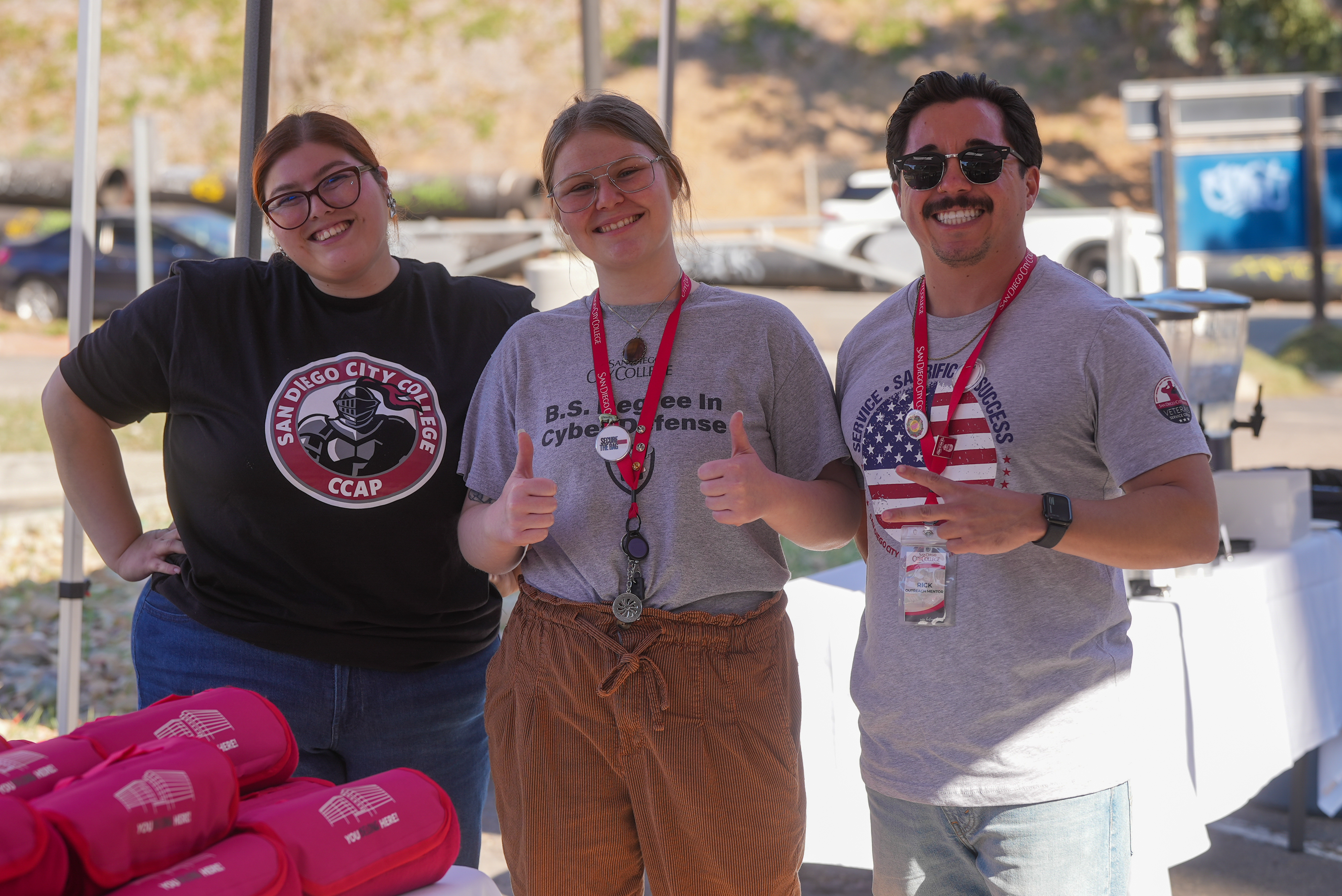 
Three helpers handing out City College swag to attendees.
