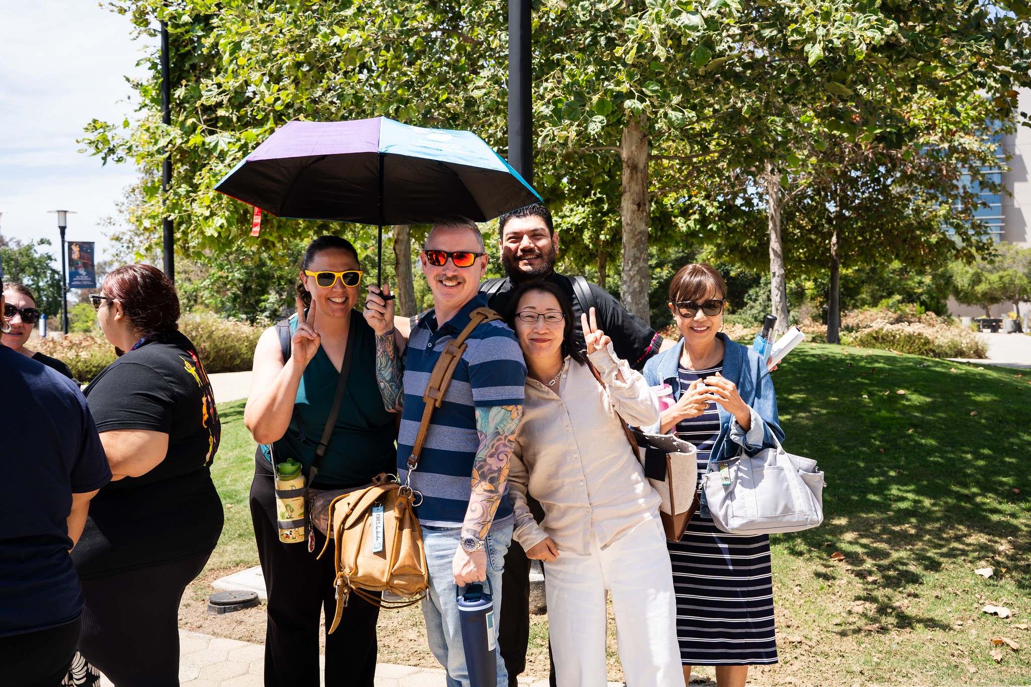 
Five people under a district umbrella pose for a group photo.
