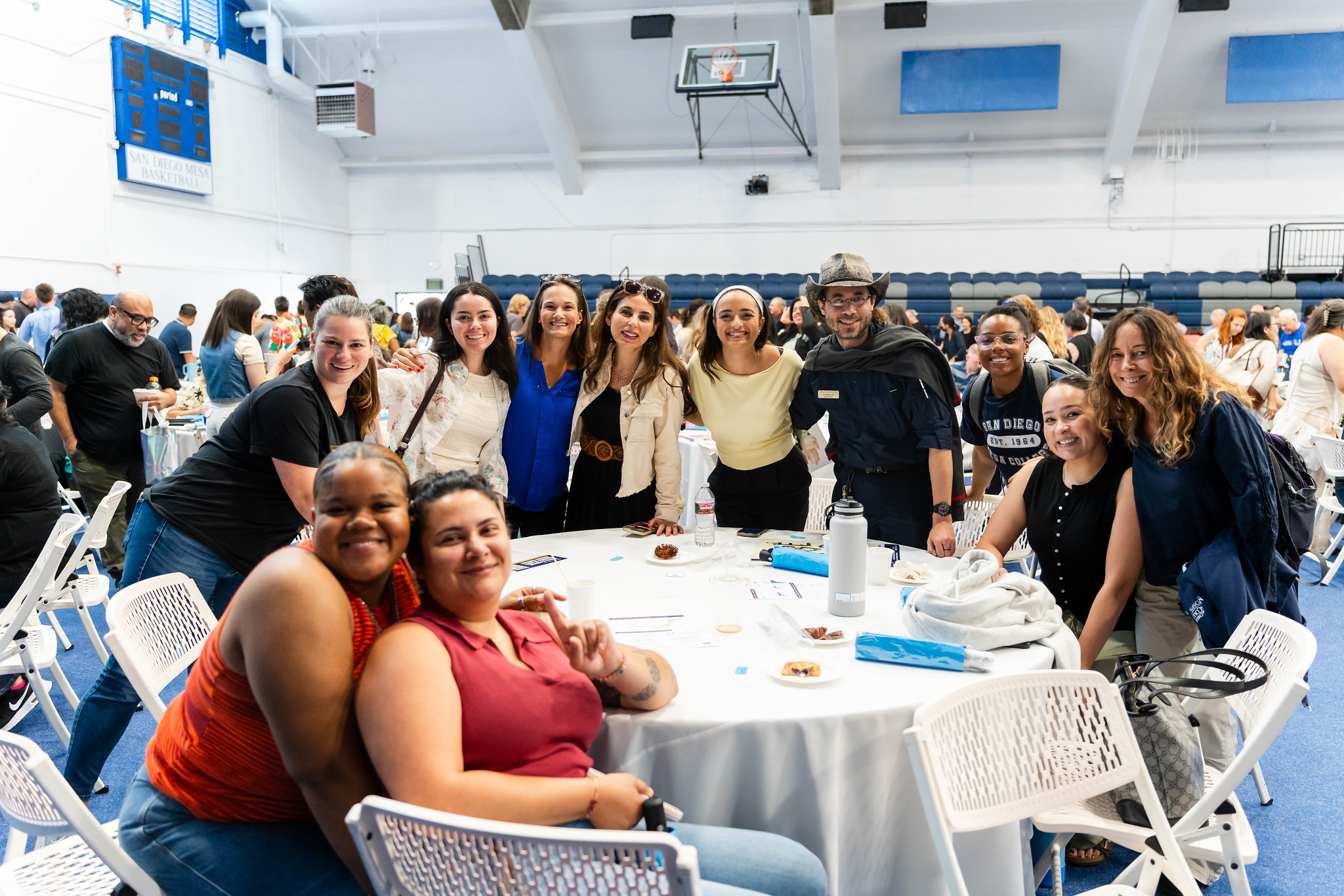 
Eleven people gather around a table for a group photo
