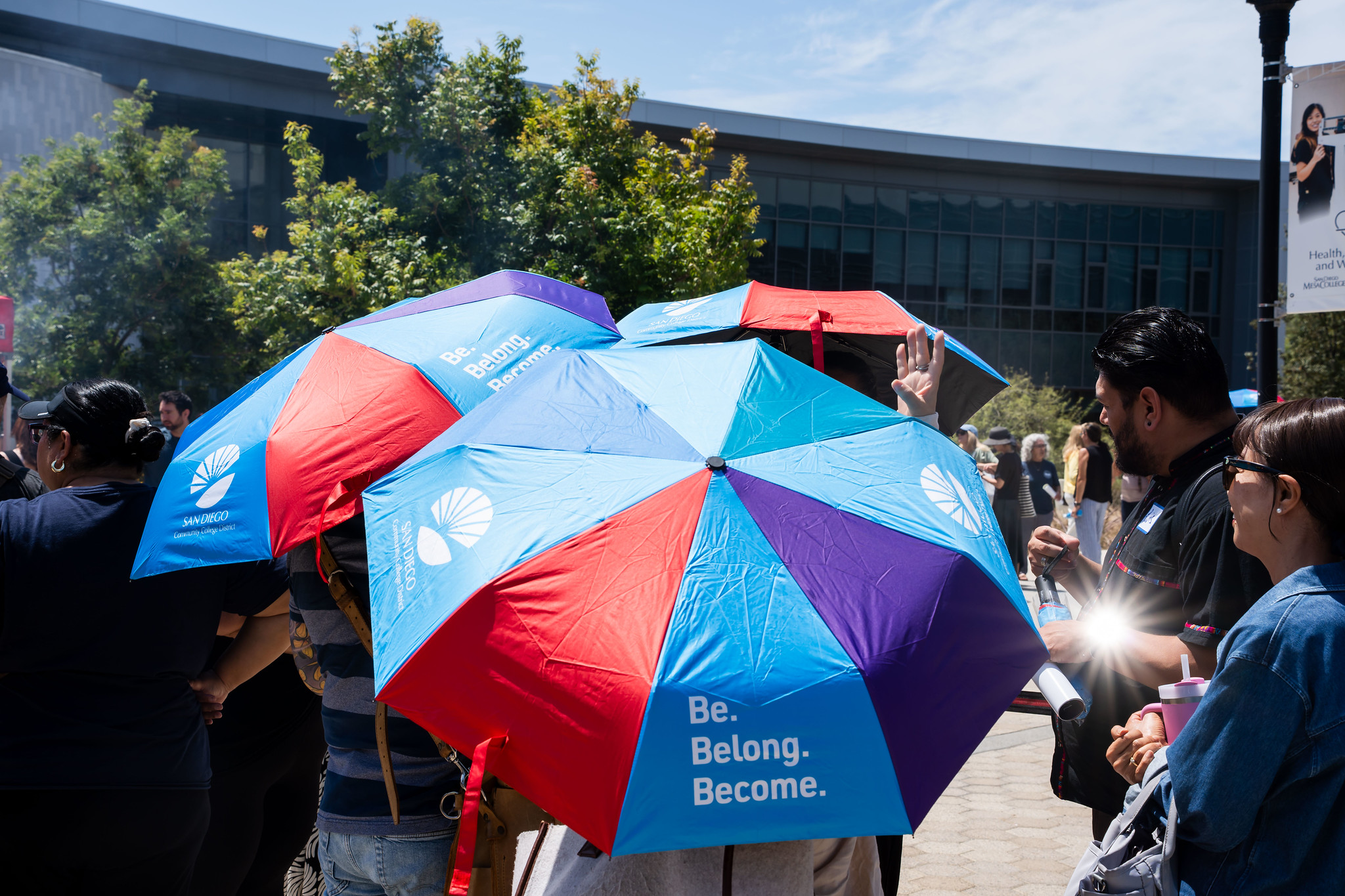 
Three district umbrellas shield people from the sun. Umbrellas were given to employees at convocation.
