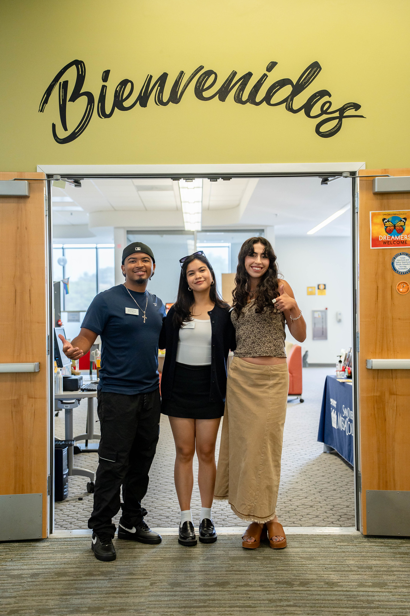 
Three workers stand in a doorway. Bienvenidos is written above the door.
