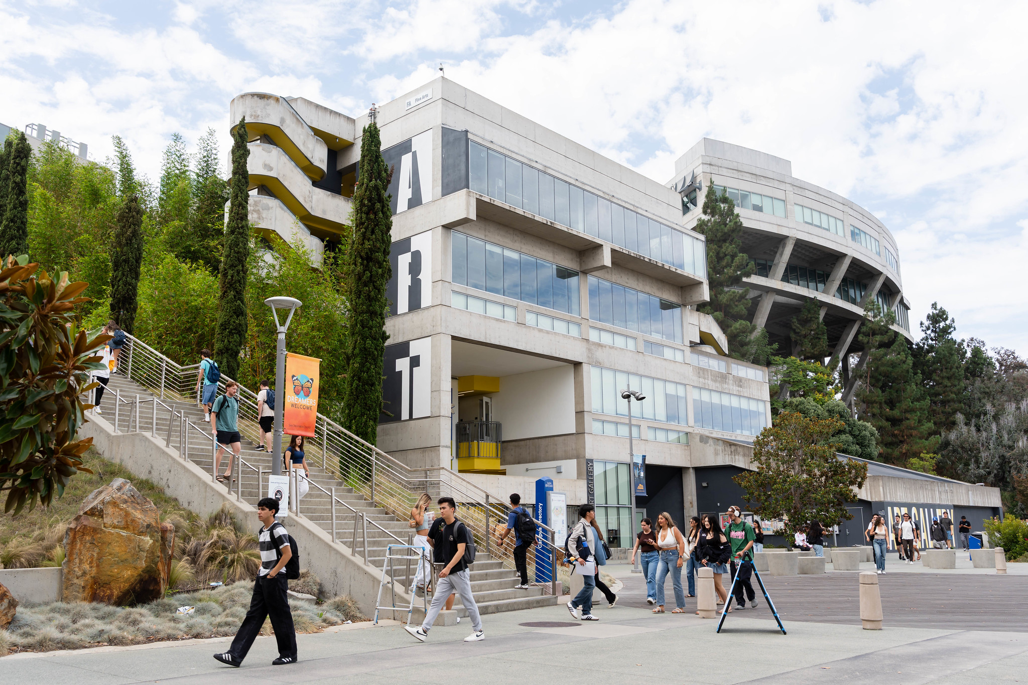 
People walking on campus near a steep staircase and the Art Gallery.
