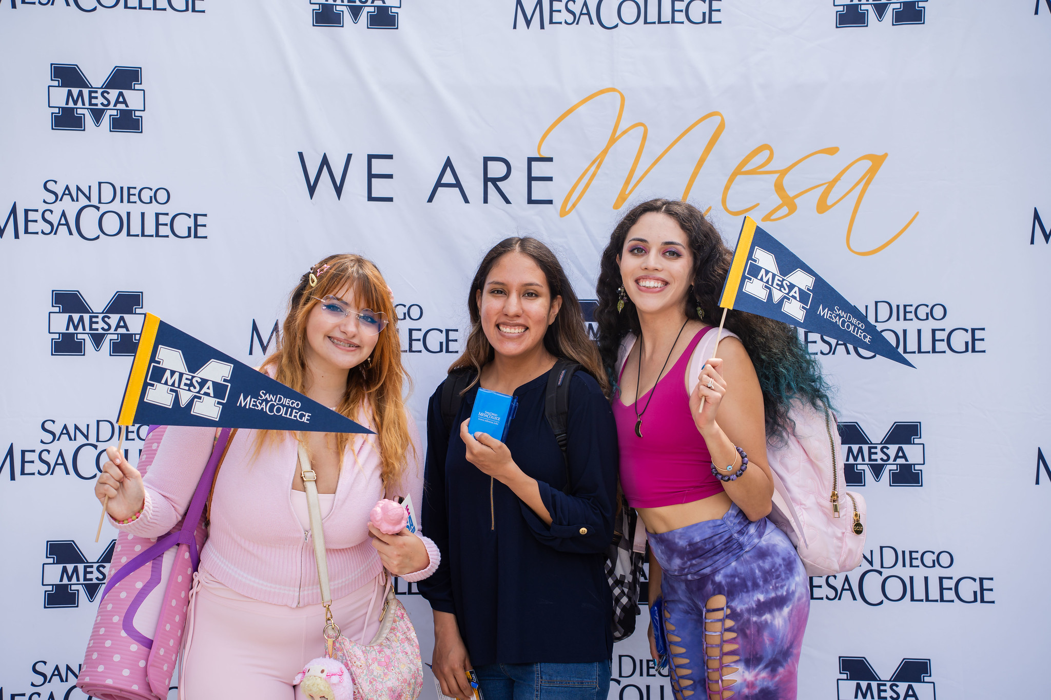
Three students pose with hand-held Mesa banners
