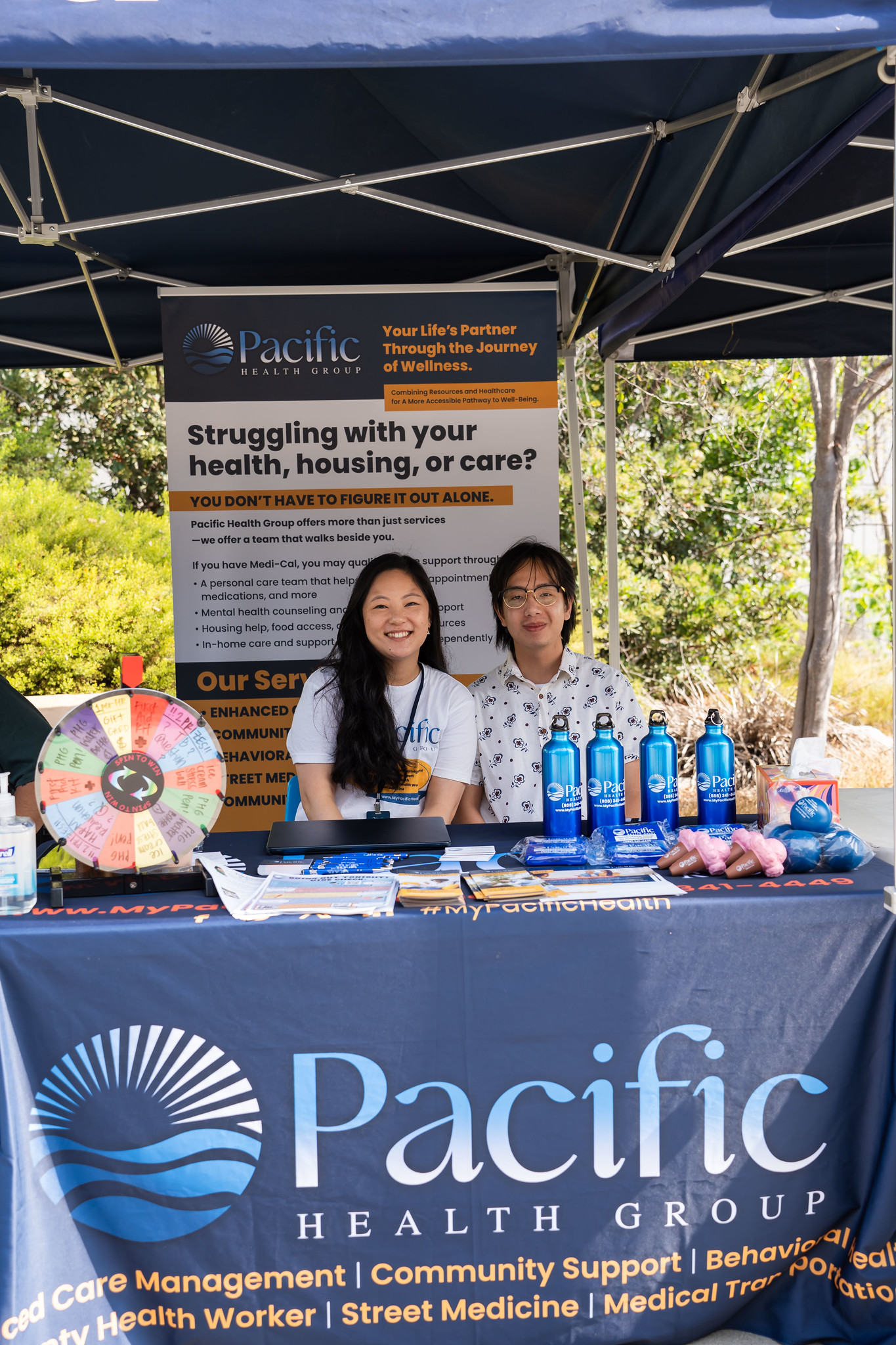 
Two people sit at a welcome table for Pacific Health Group.
