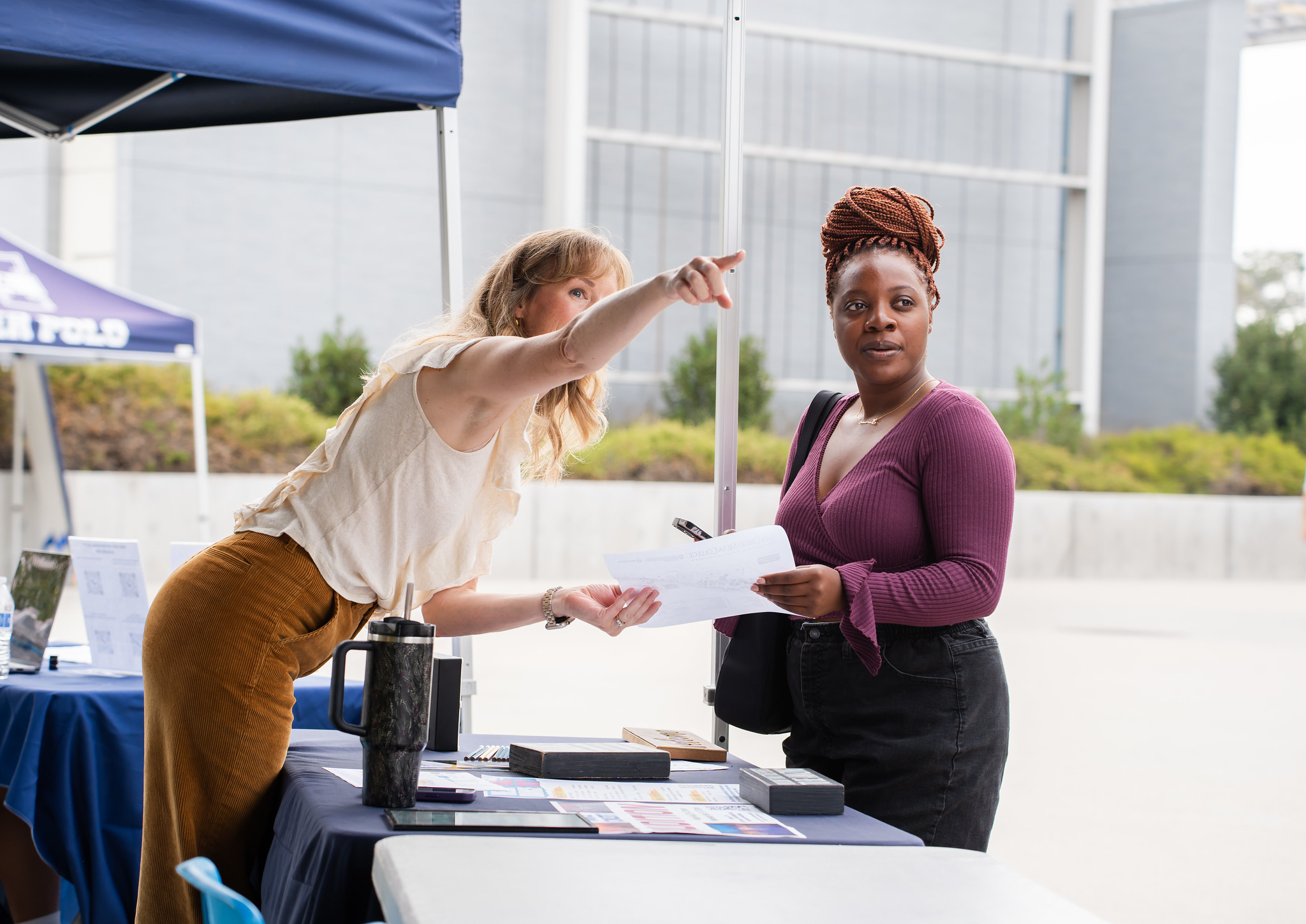 
A worker at a welcome booth points and gives a student directions
