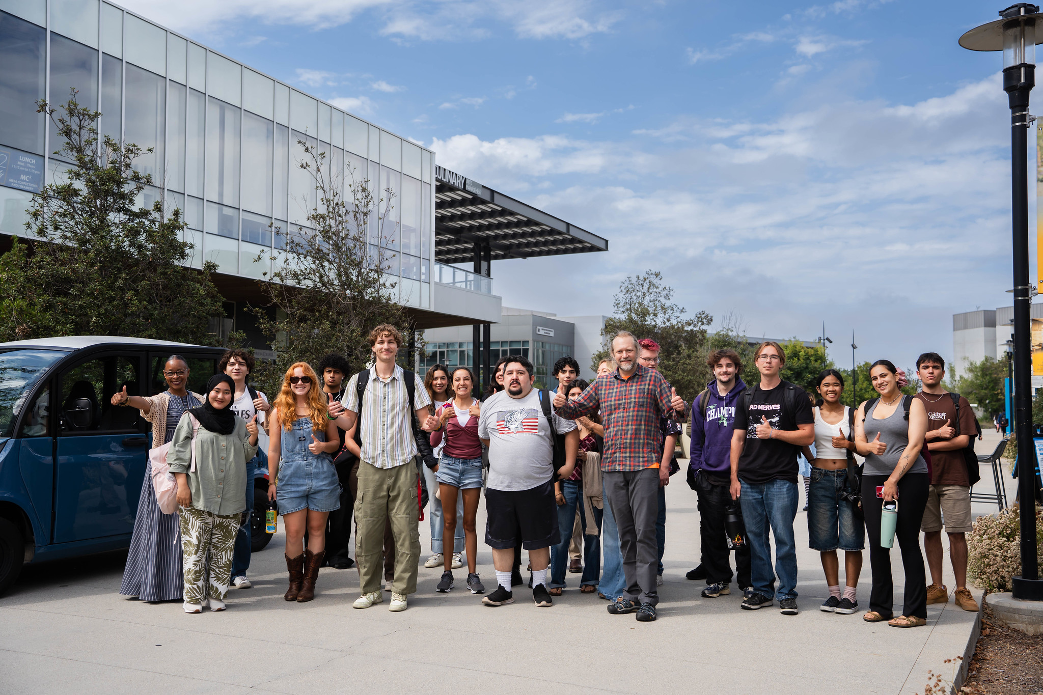 
Twenty people gather for a group photo outside on campus.
