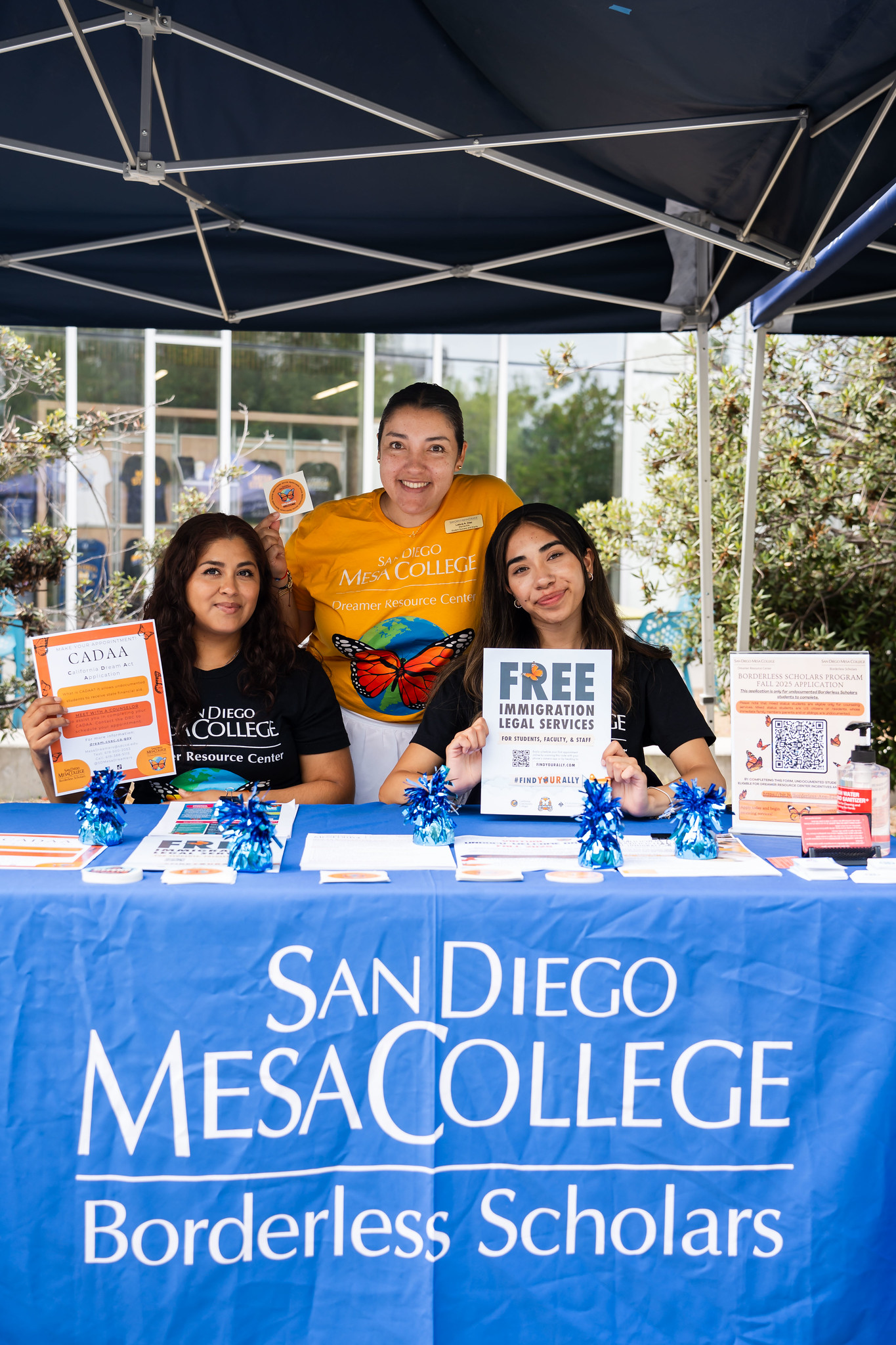 
Three people at the borderless scholars welcome tent.
