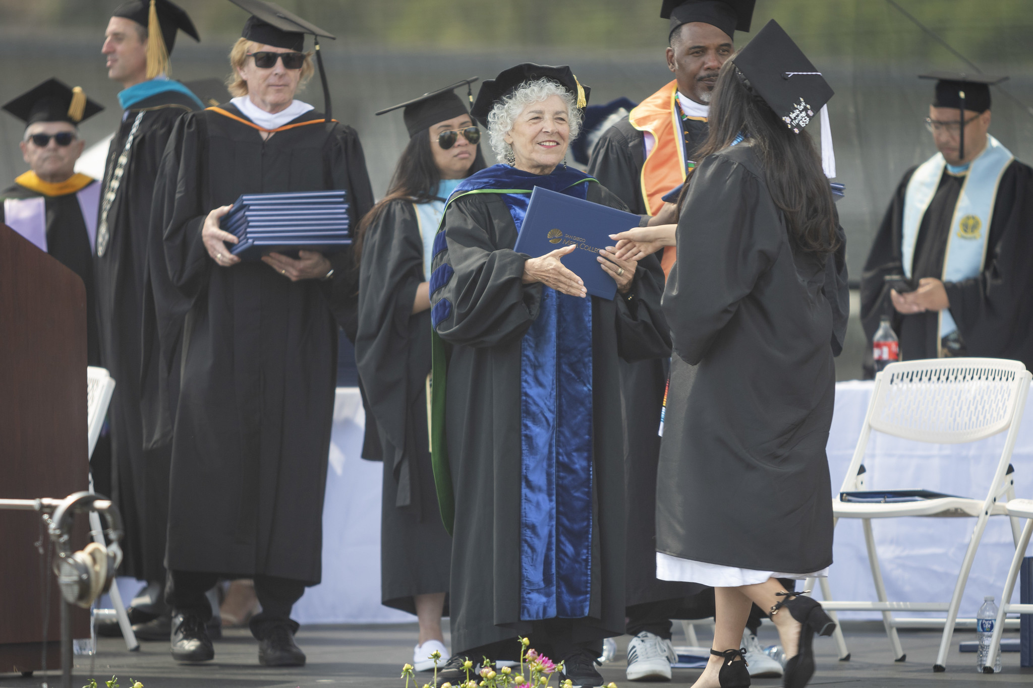 
Trustee Maria Nieto Senour shakes a graduate's hand and gives her a diploma.
