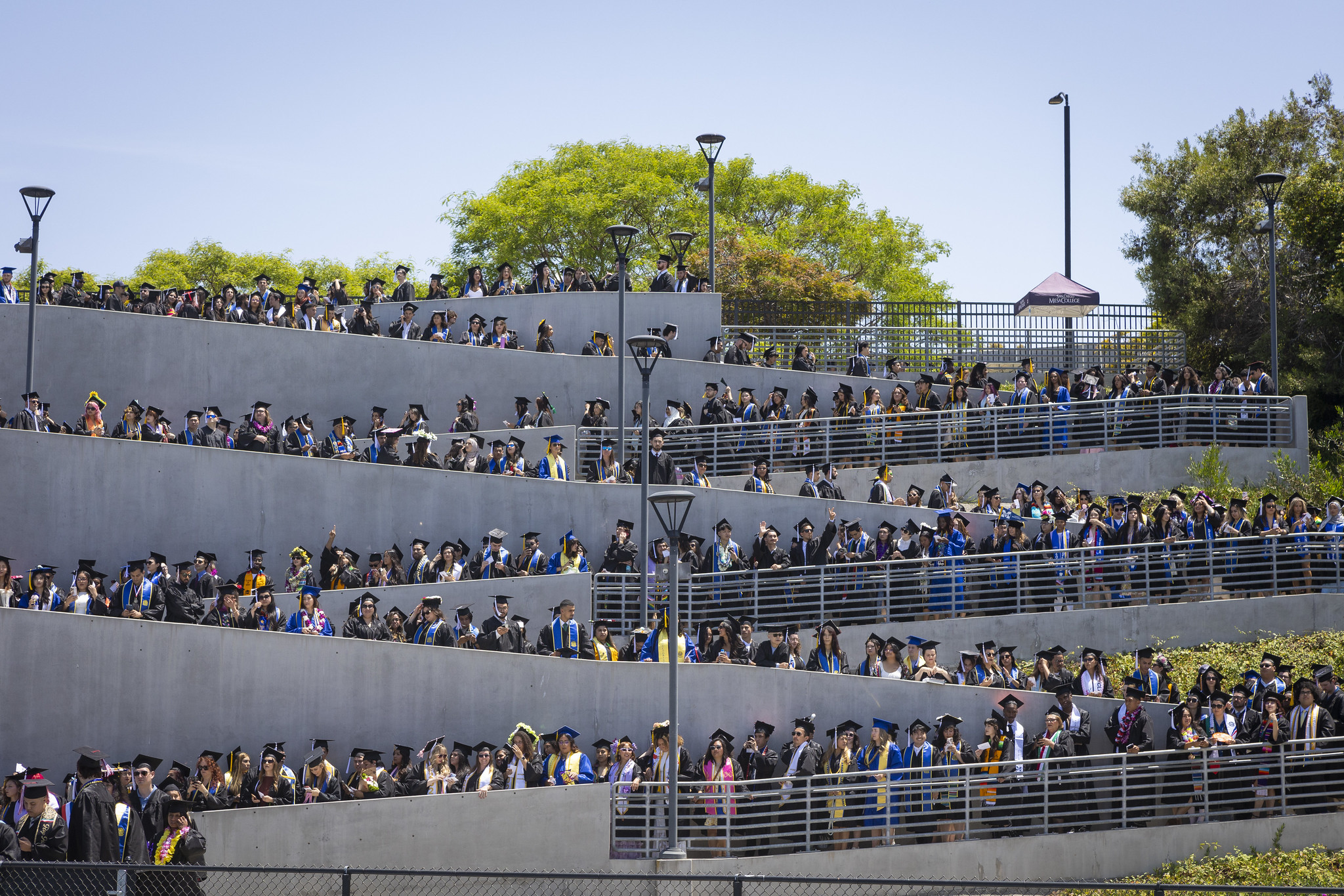 
Graduates form a zig zag formation as they walk down the five levels of a ramp to get to the field of the stadium.
