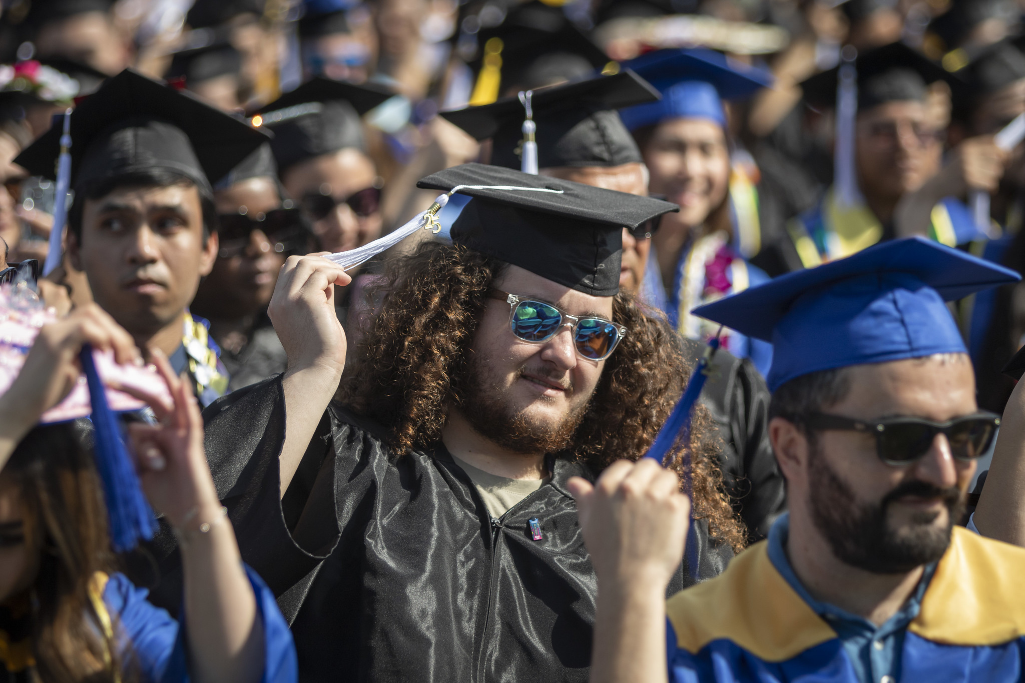 
A group of graduates are seated and turning their tassles to mark their graduation.
