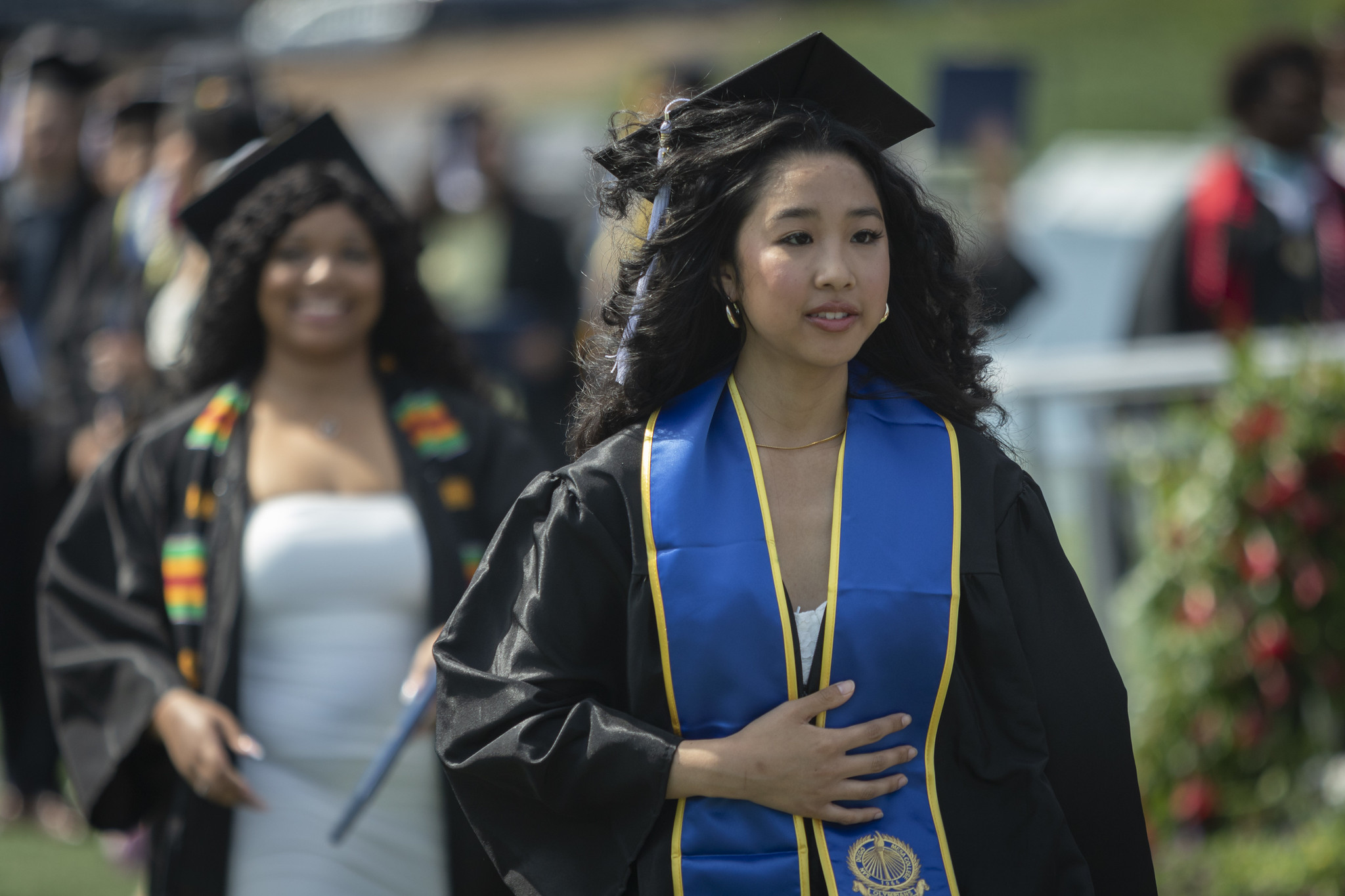 
A graduate smiling in the crowd, holding her degree.
