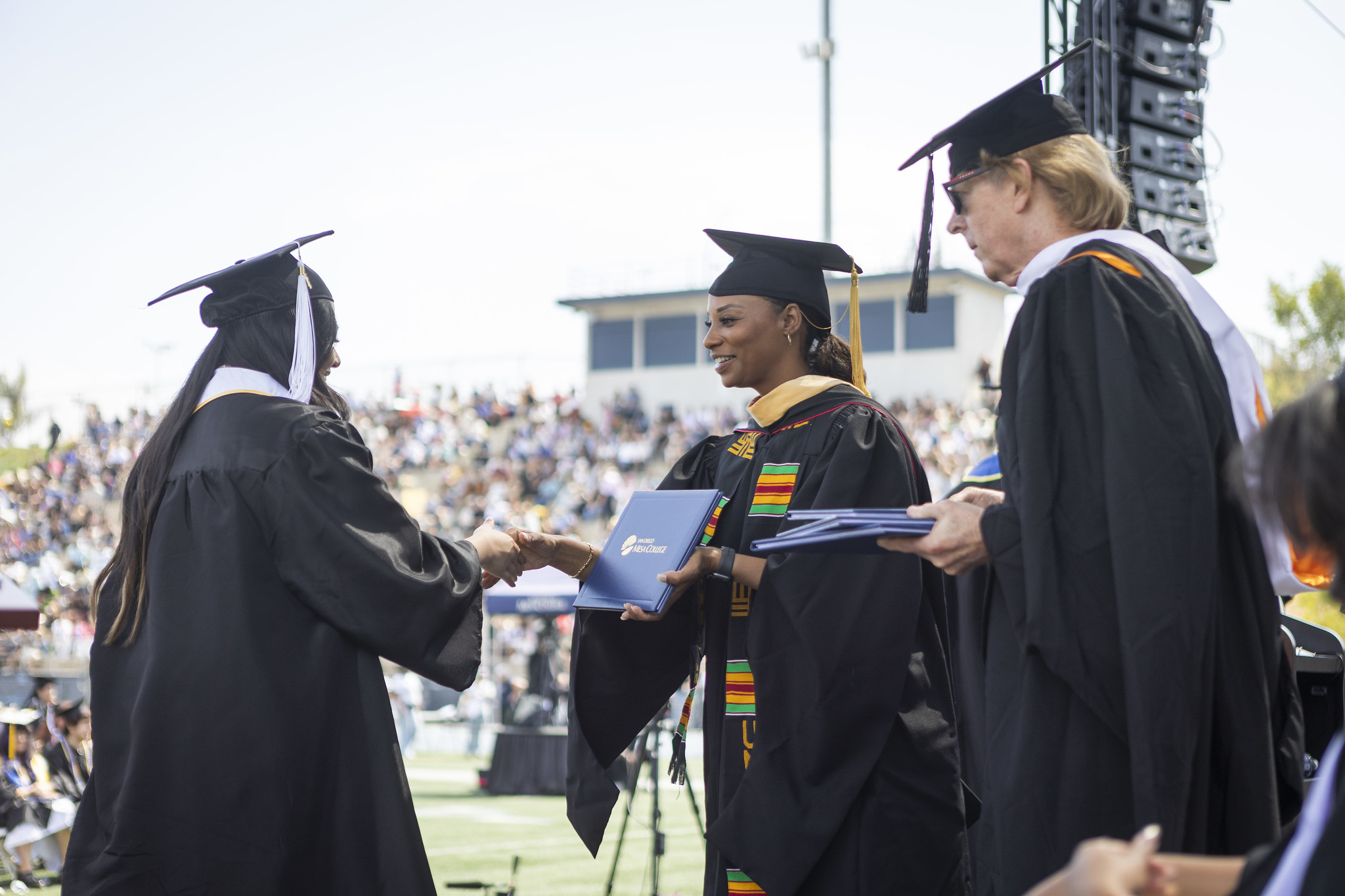 
Trustee Mariah Jameson shakes hands with a graduate and gives her a degree.

