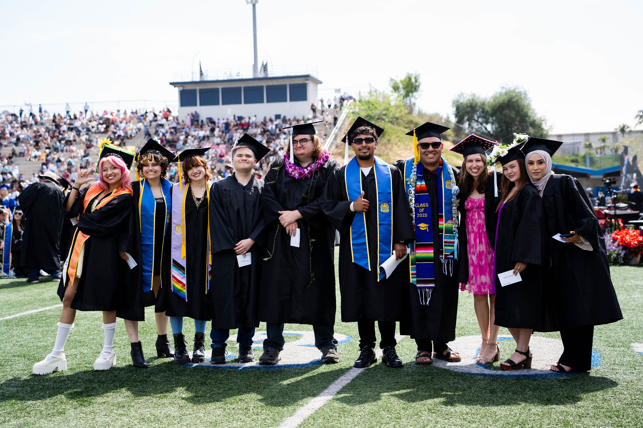 
Ten graduates line up for a group photo on the field at commencement.
