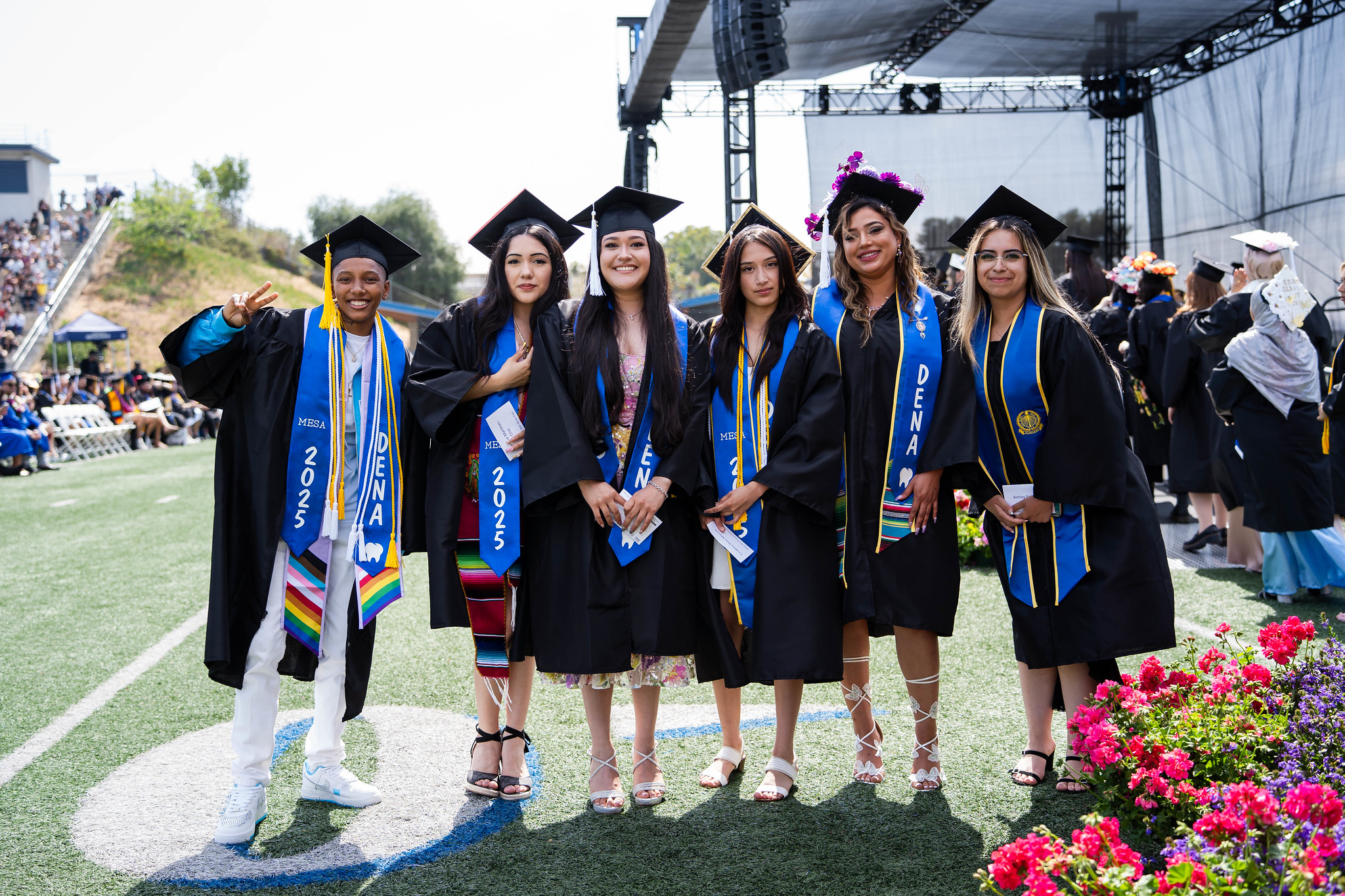 
Six graduates line up for a group photo on the field at commencement.
