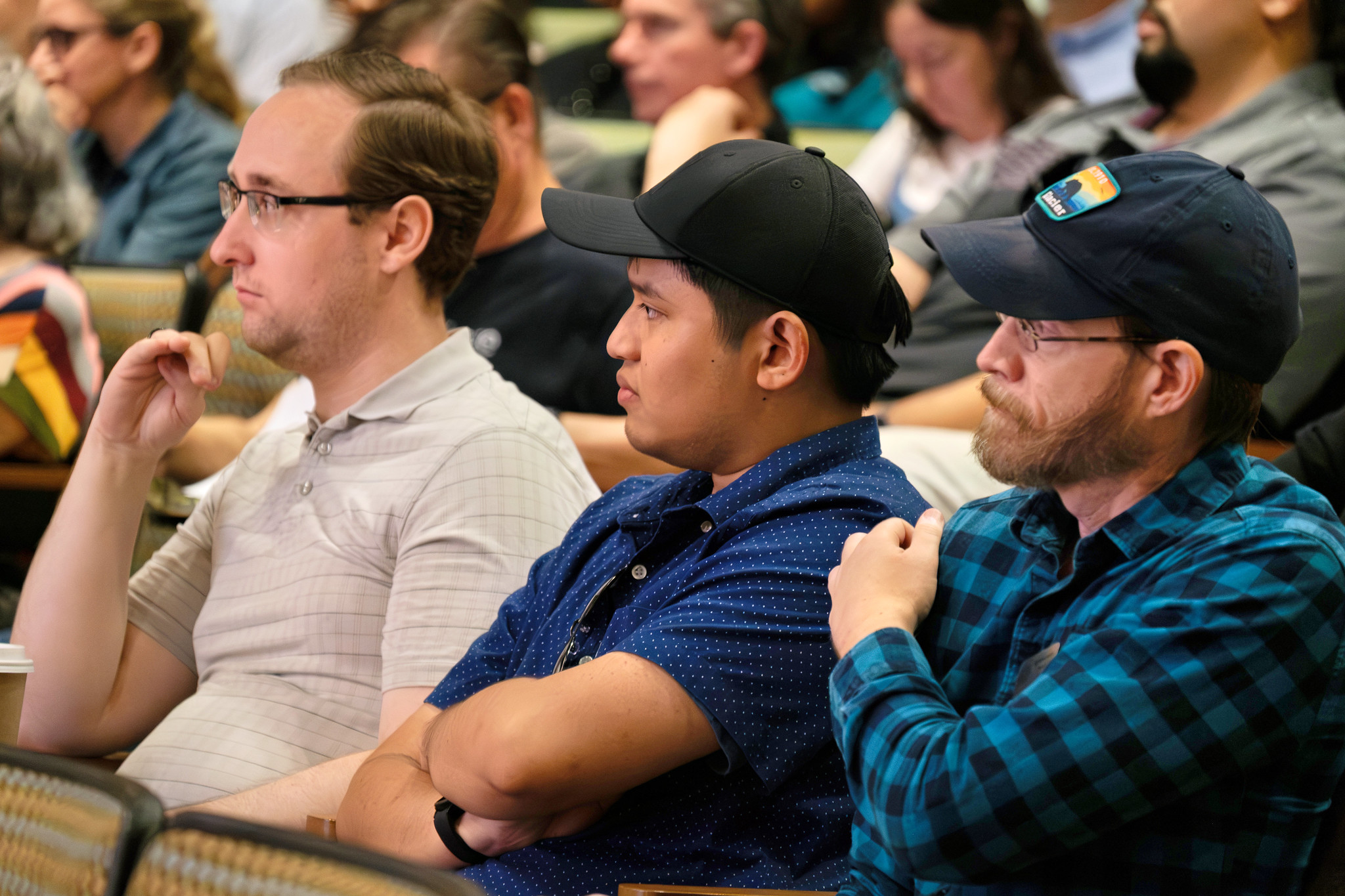 
Three people in the audience watch the presentation.
