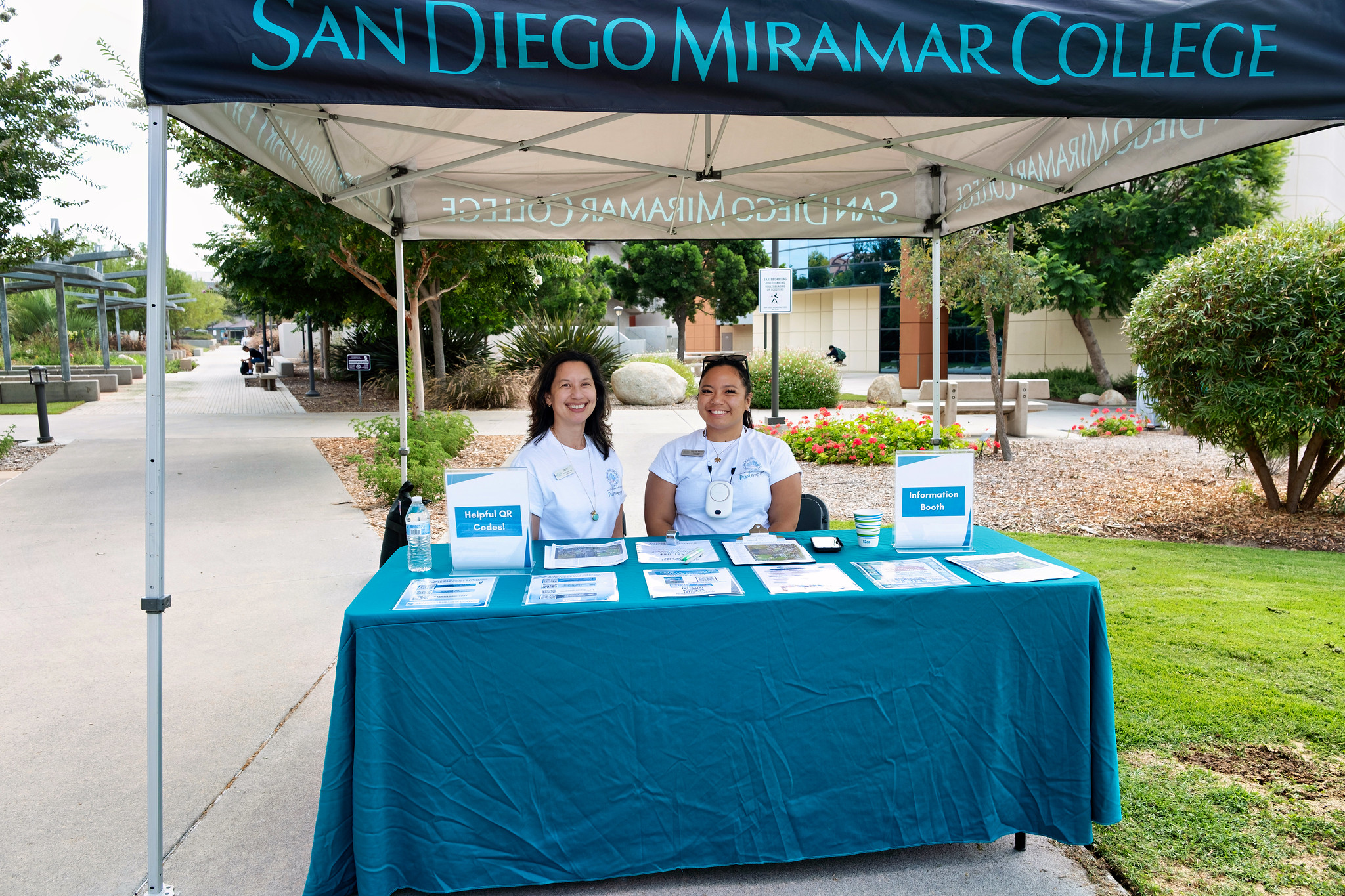 
Two people sit at a welcome tent.
