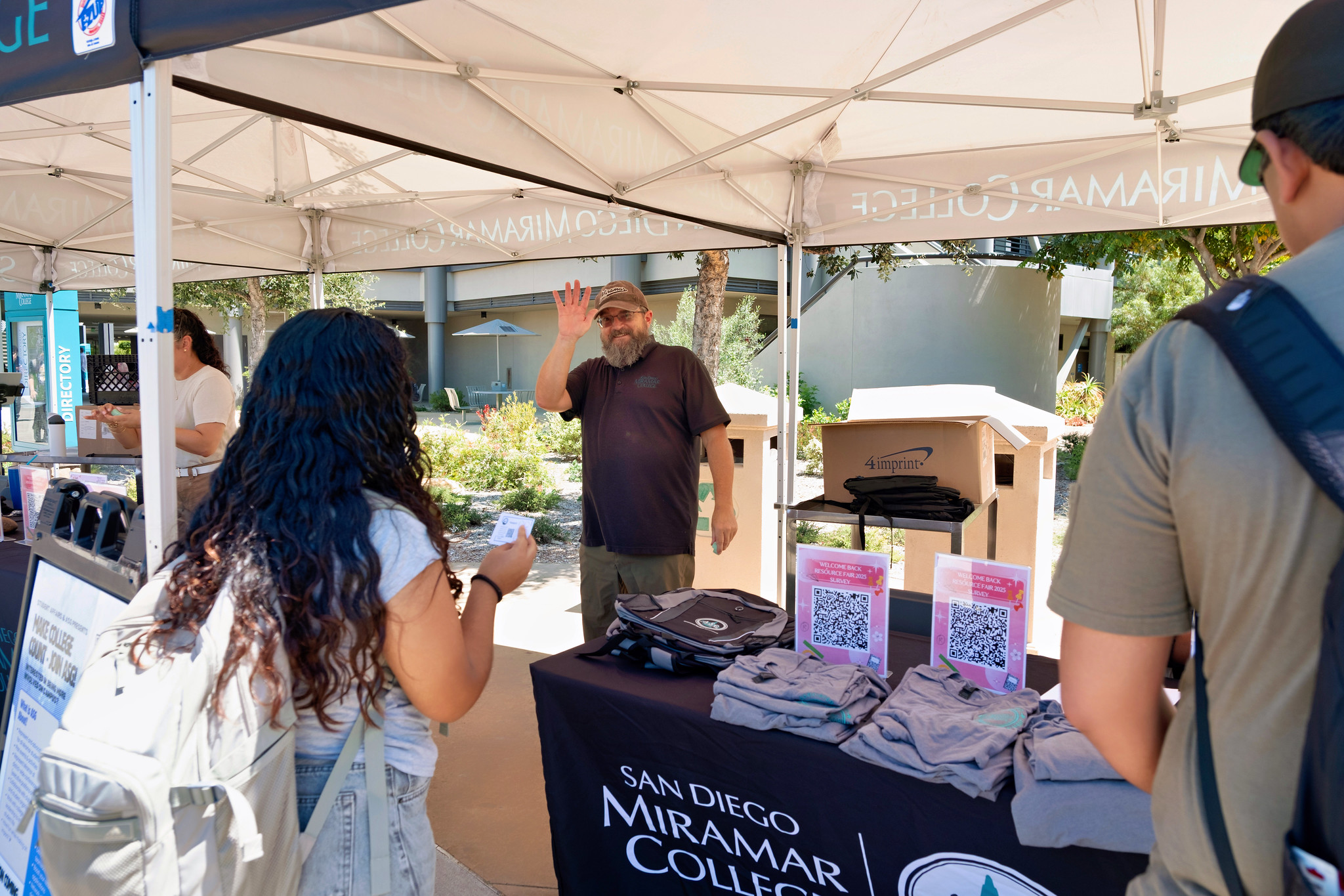 
An employee handing out Miramar swag waves to the camera.
