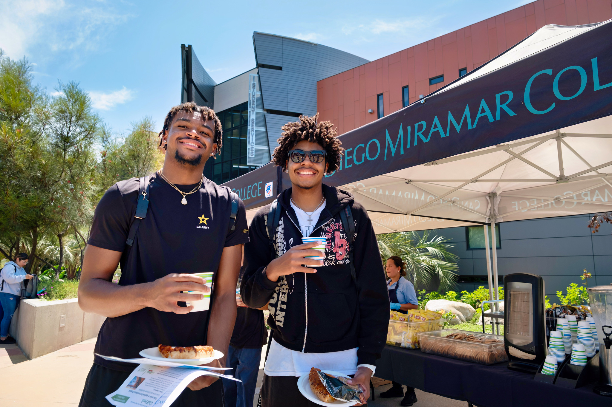 
Two students in front of a row of welcome booths.
