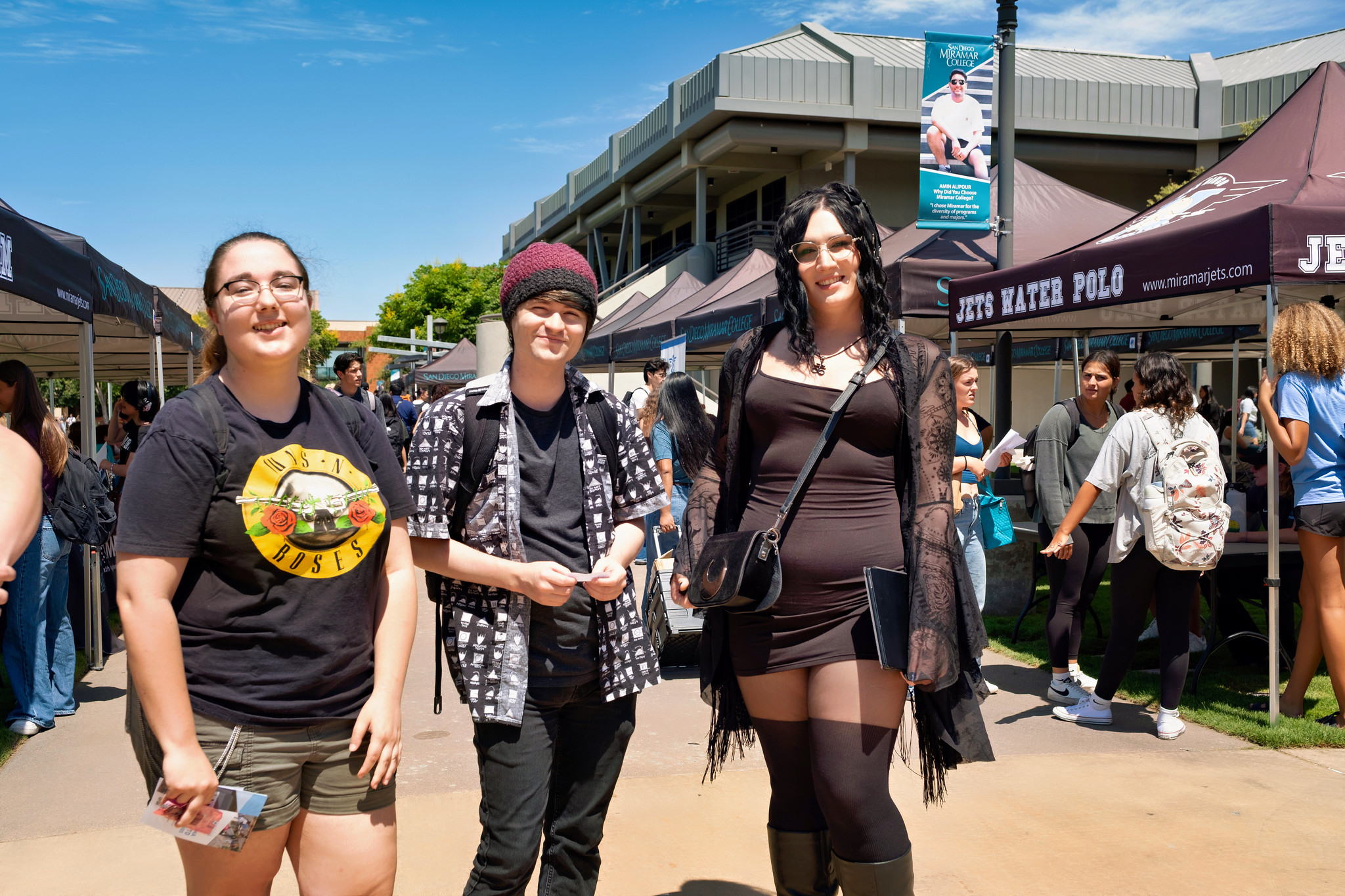 
Three students on campus near a row of welcome tents.

