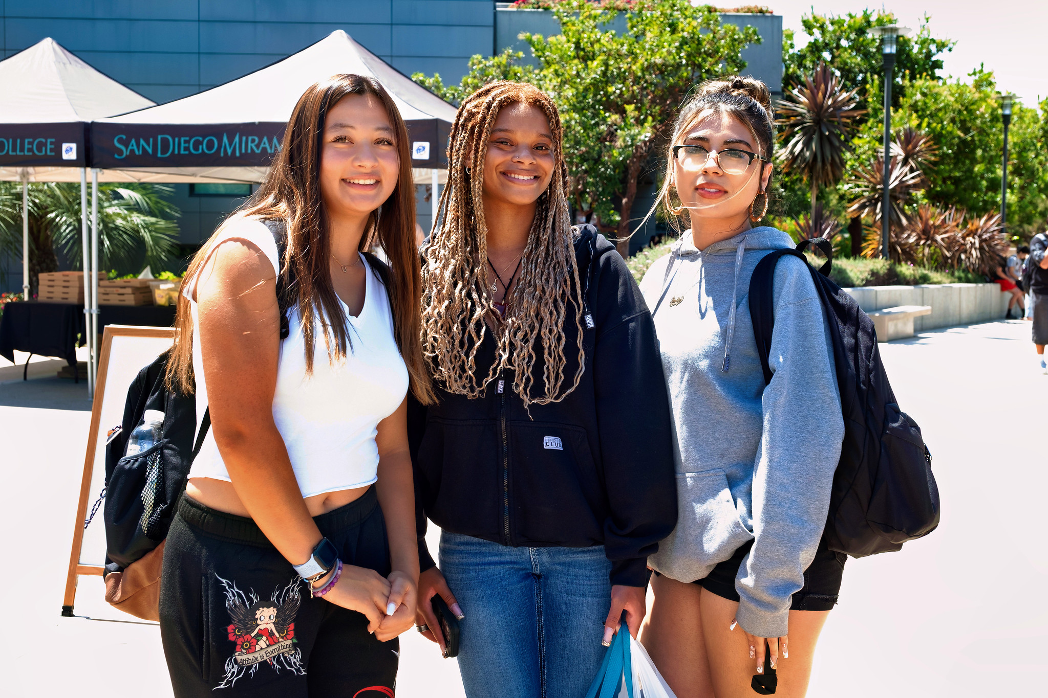 
Three students on campus near a row of welcome tents.
