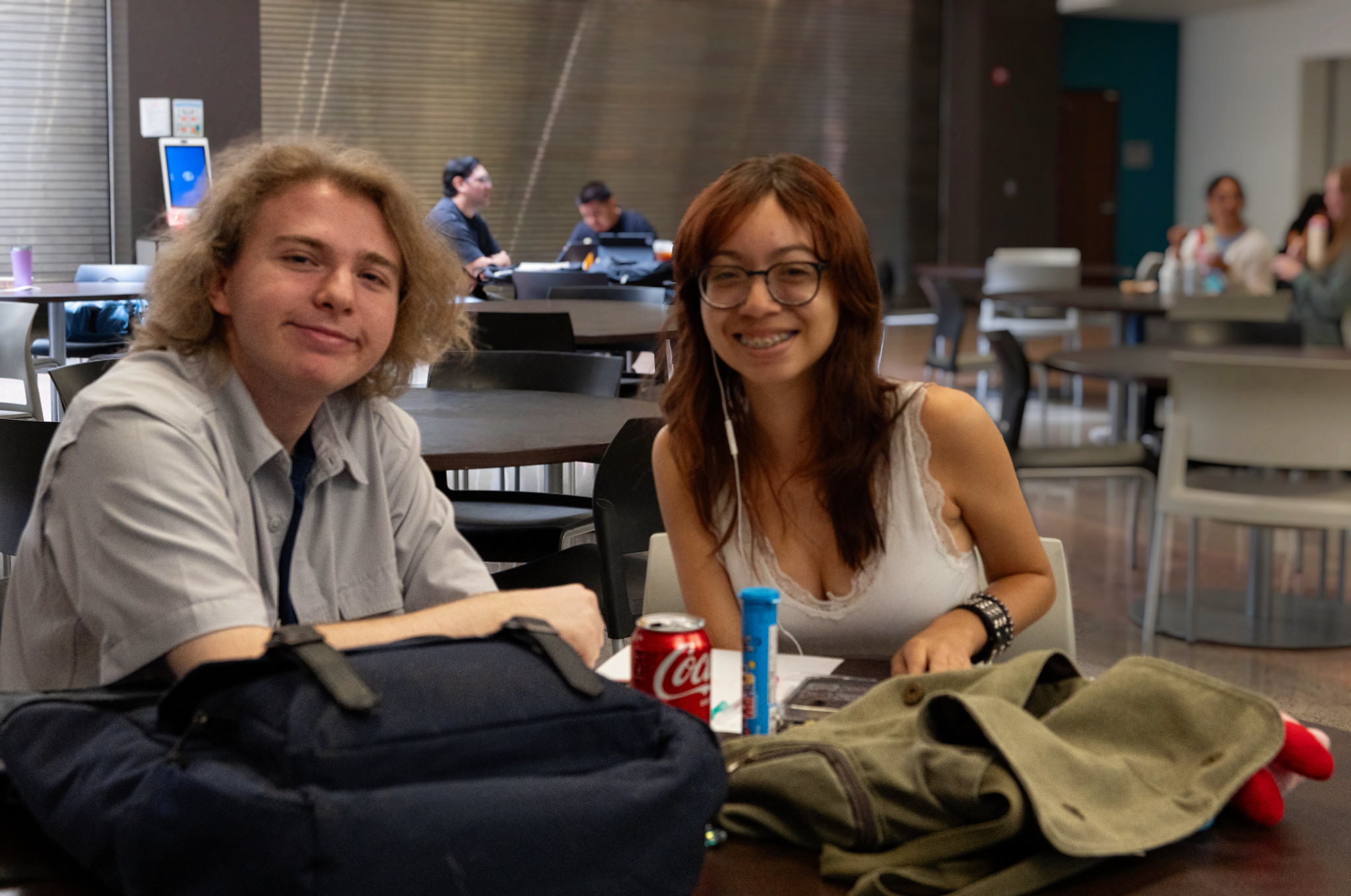 
Two people look at notes at a table with bookbags and snacks
