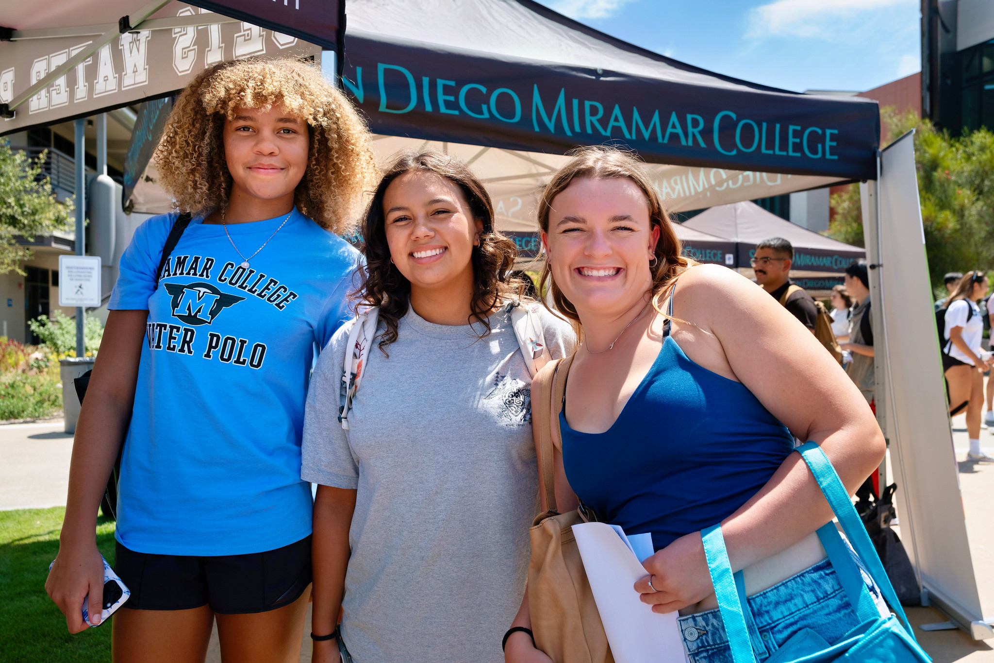 
Three students stand in front of a Miramar welcome tent.&nbsp;
