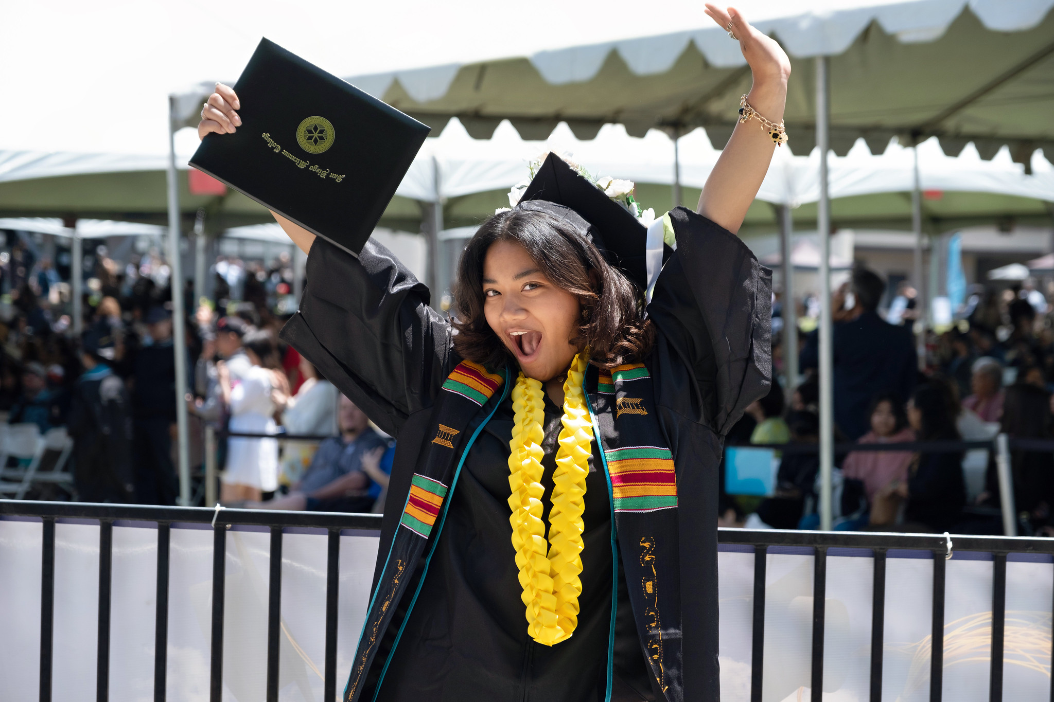 
A student cheers and holds up her degree.
